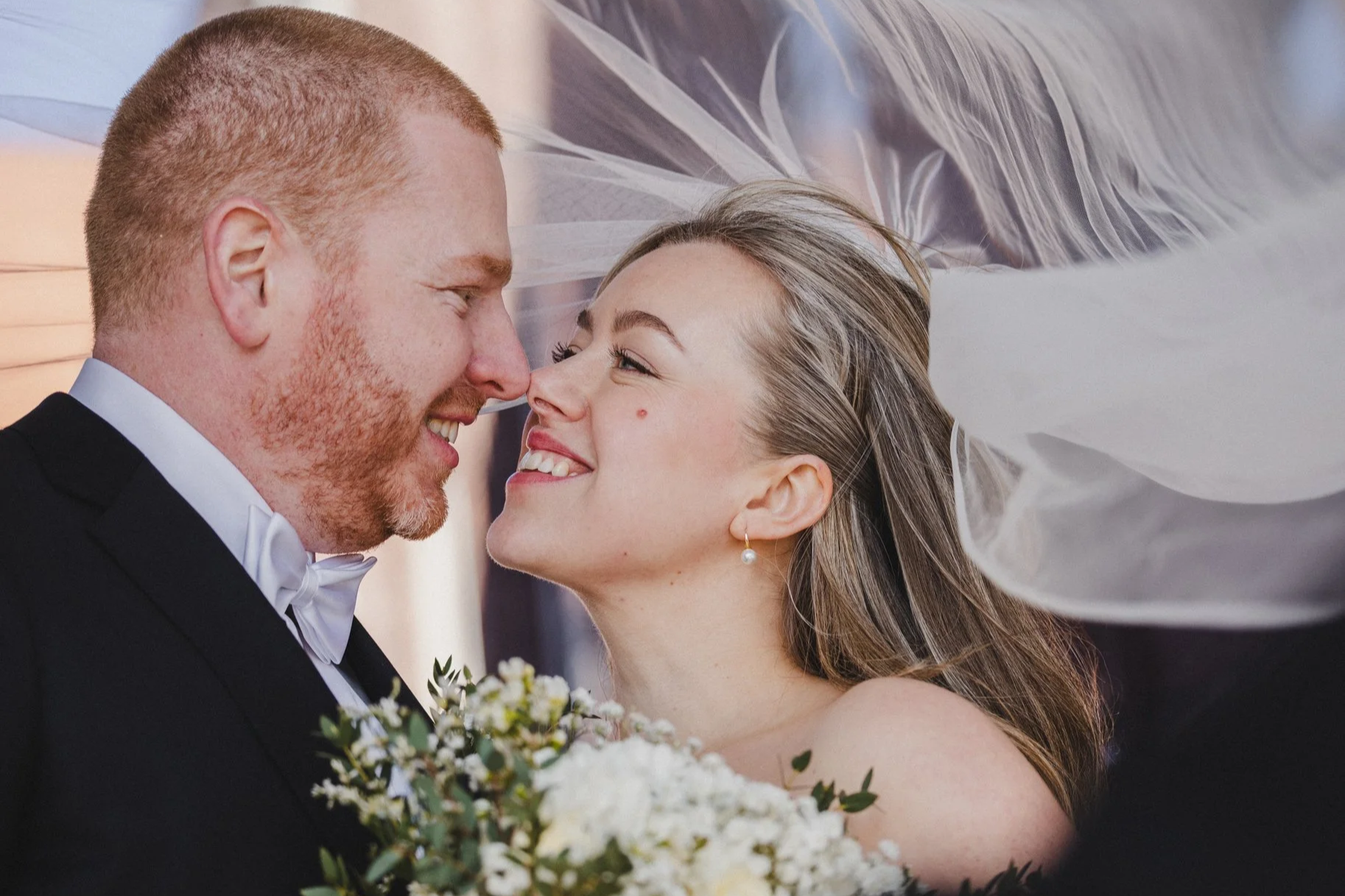 A bride and groom smiling and touching noses, close-up of their faces during a wedding celebration.