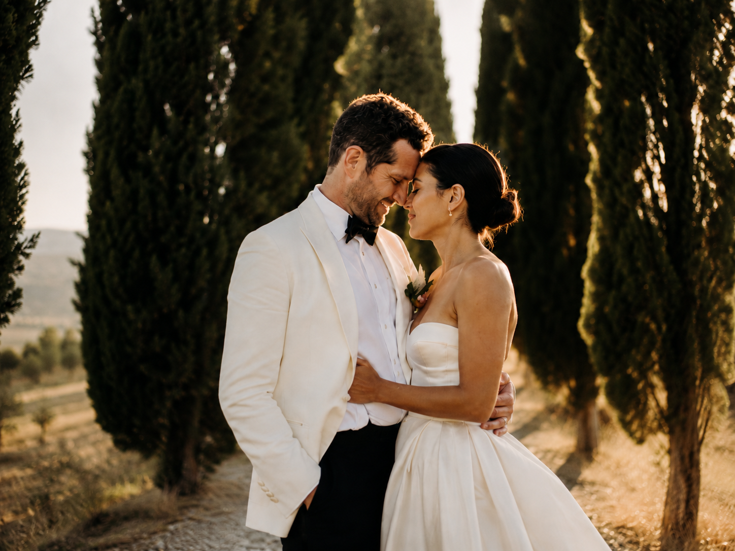 Romantic sunset wedding portrait of a bride and groom among the iconic cypress trees at Borgo Stomennano in Tuscany.