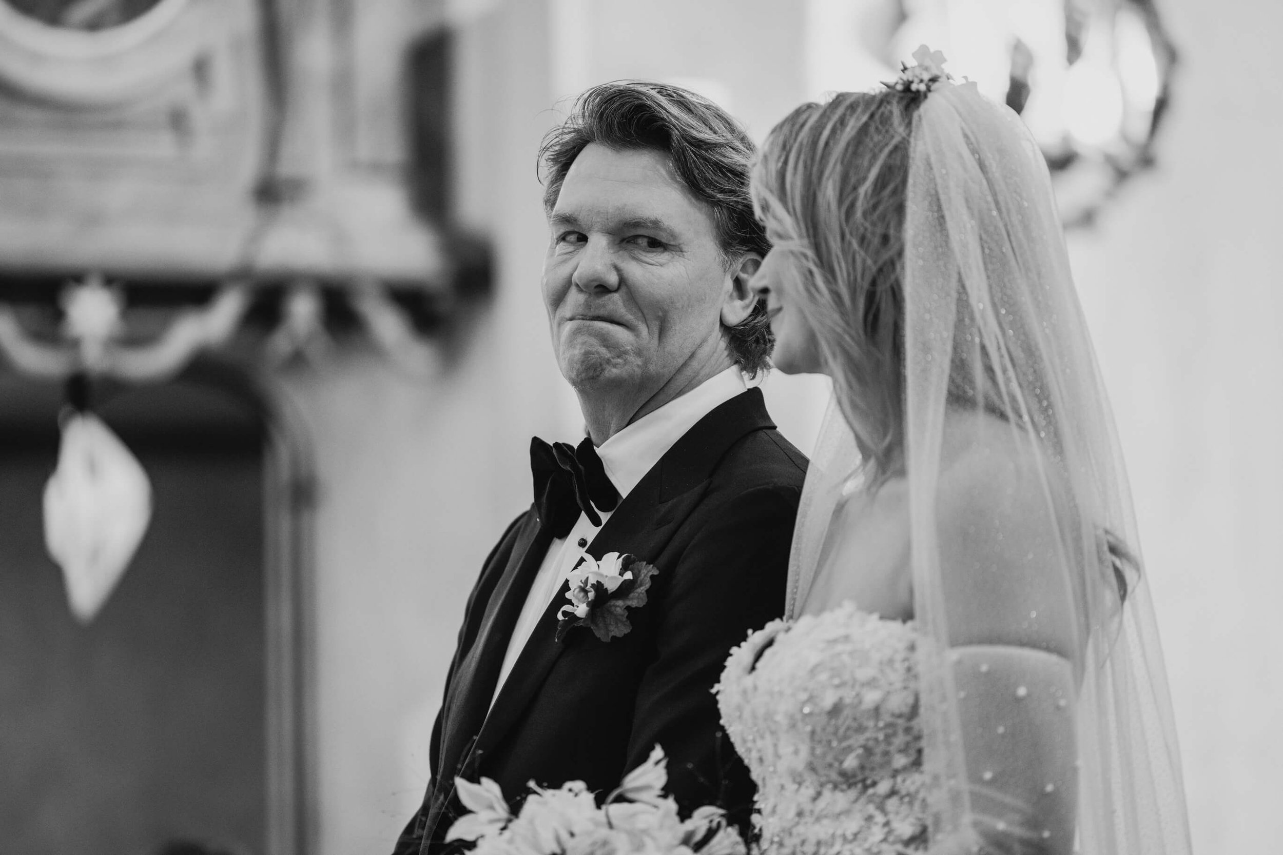 Emotional black-and-white portrait of a groom looking at the bride during the wedding ceremony