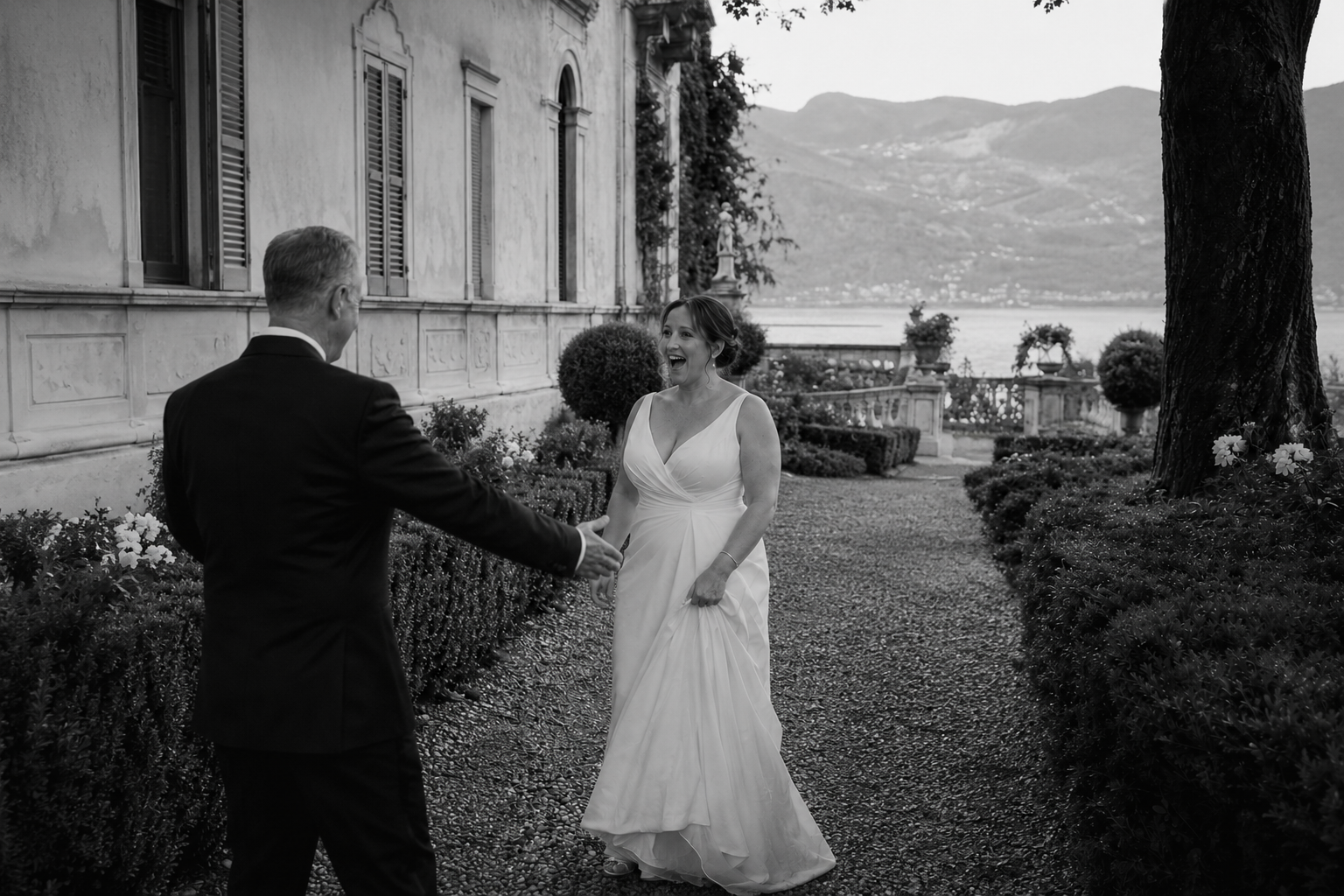 Bride and groom during a first look in the gardens of Villa Pizzo with Lake Como and mountains in the background.
