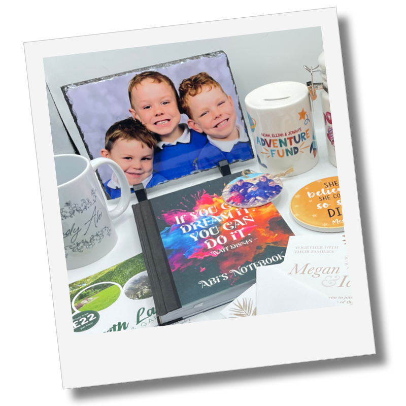 A desk display with a framed photograph of three young boys, a mug, a donation box labeled 'Adventure Fund,' a colorful notebook with the quote 'If you can dream it, you can do it' from Walt Disney, and various printed materials, likely at a special event or birthday celebration.