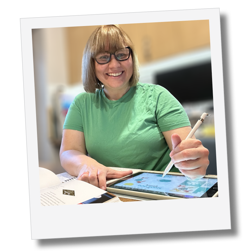 A woman with glasses and a green shirt using a stylus on a digital tablet while smiling.