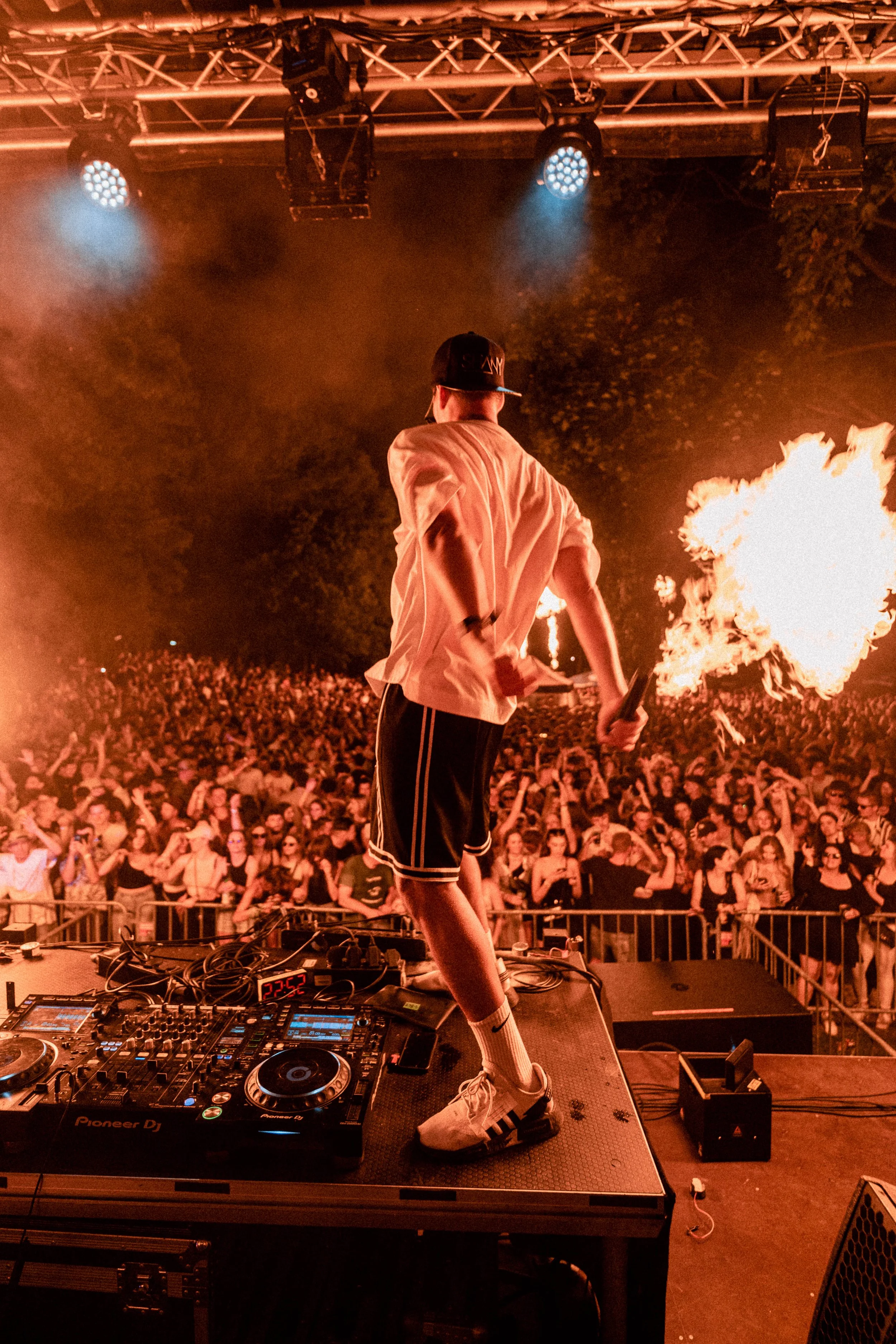 DJ auf einer Bühne beim Feuer speien vor einer großen Menschenmenge bei einem Festival in der Nacht.
