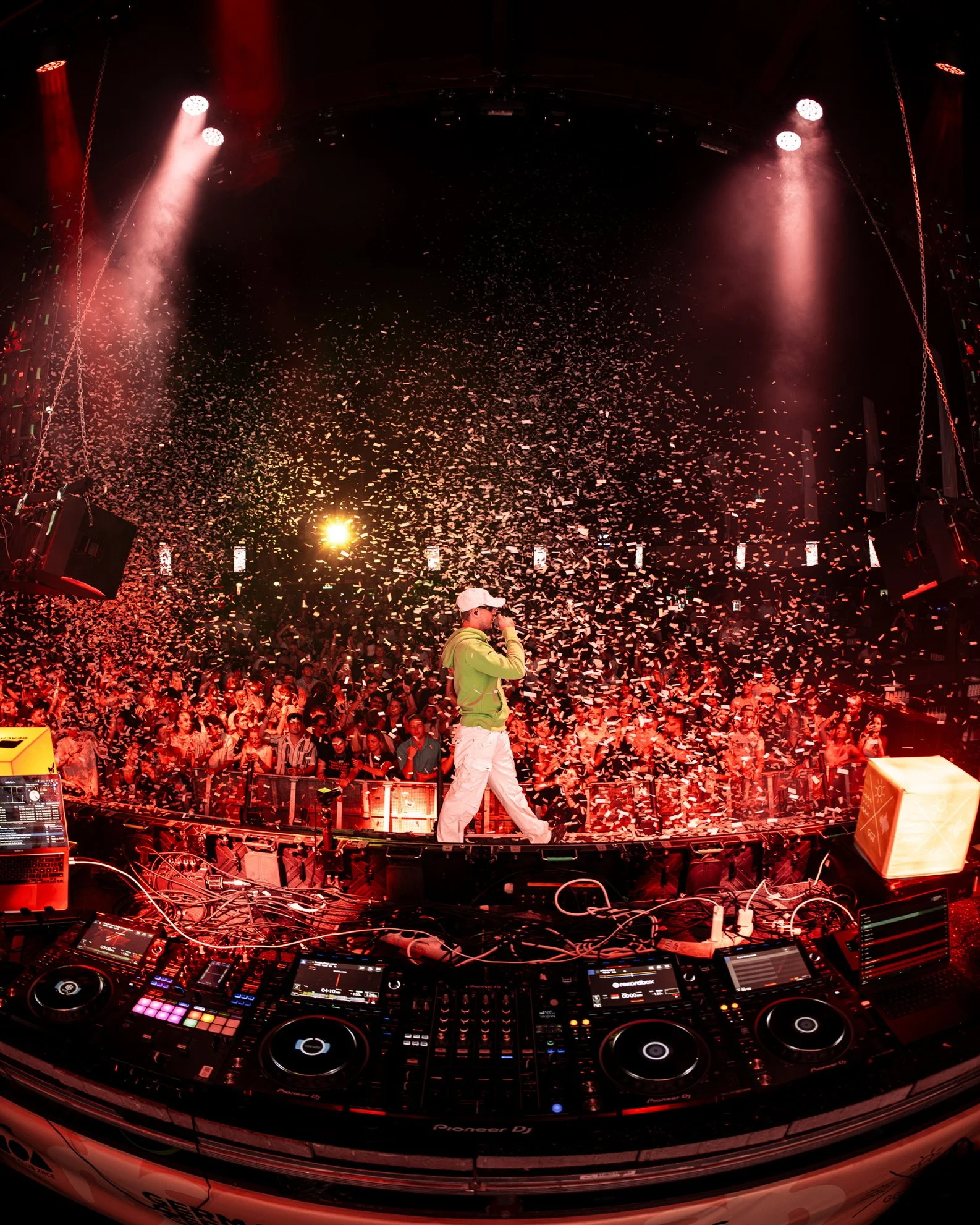 DJ auf einer Bühne mit Publikum und Konfetti, rote Beleuchtung, Musikercdengestaltung