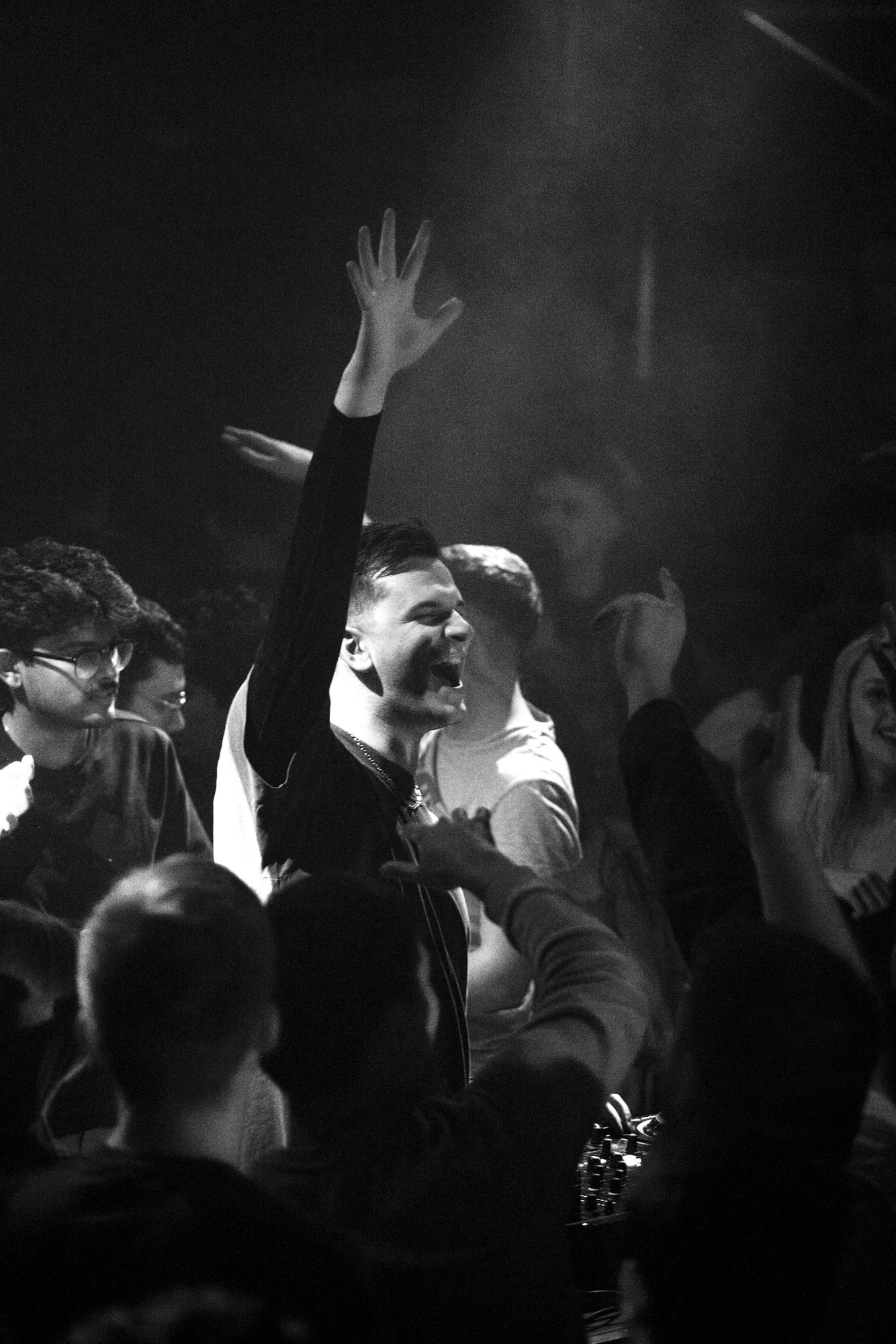 Menschen feiern und tanzen in einer dunklen, lustigen Umgebung, einige mit erhobenen Armen.