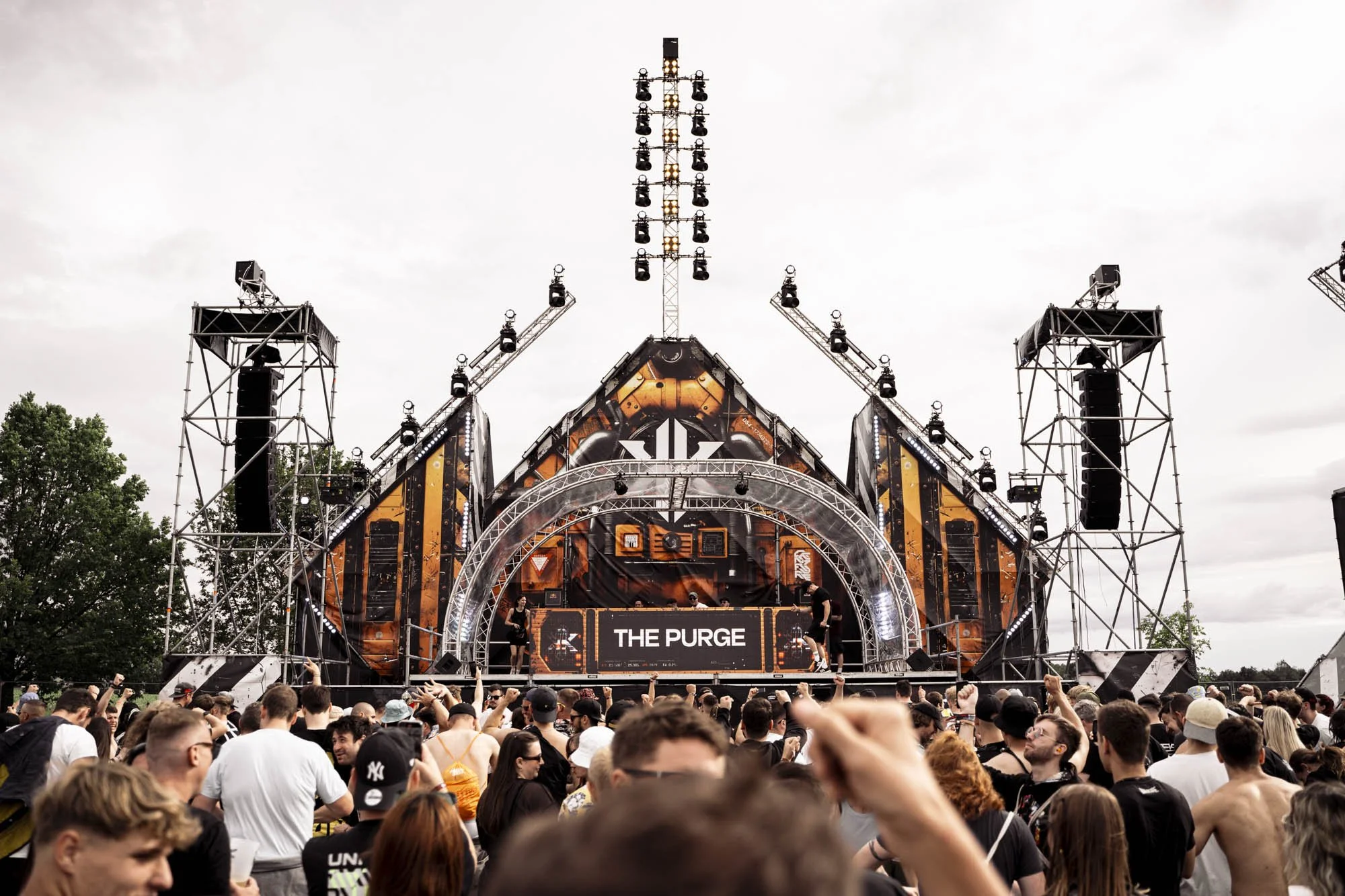 Großes Musikfestival im Freien mit einer größten Bühne, technische Anlage und Publikum, das die Musik genießt, bei bewölktem Himmel.