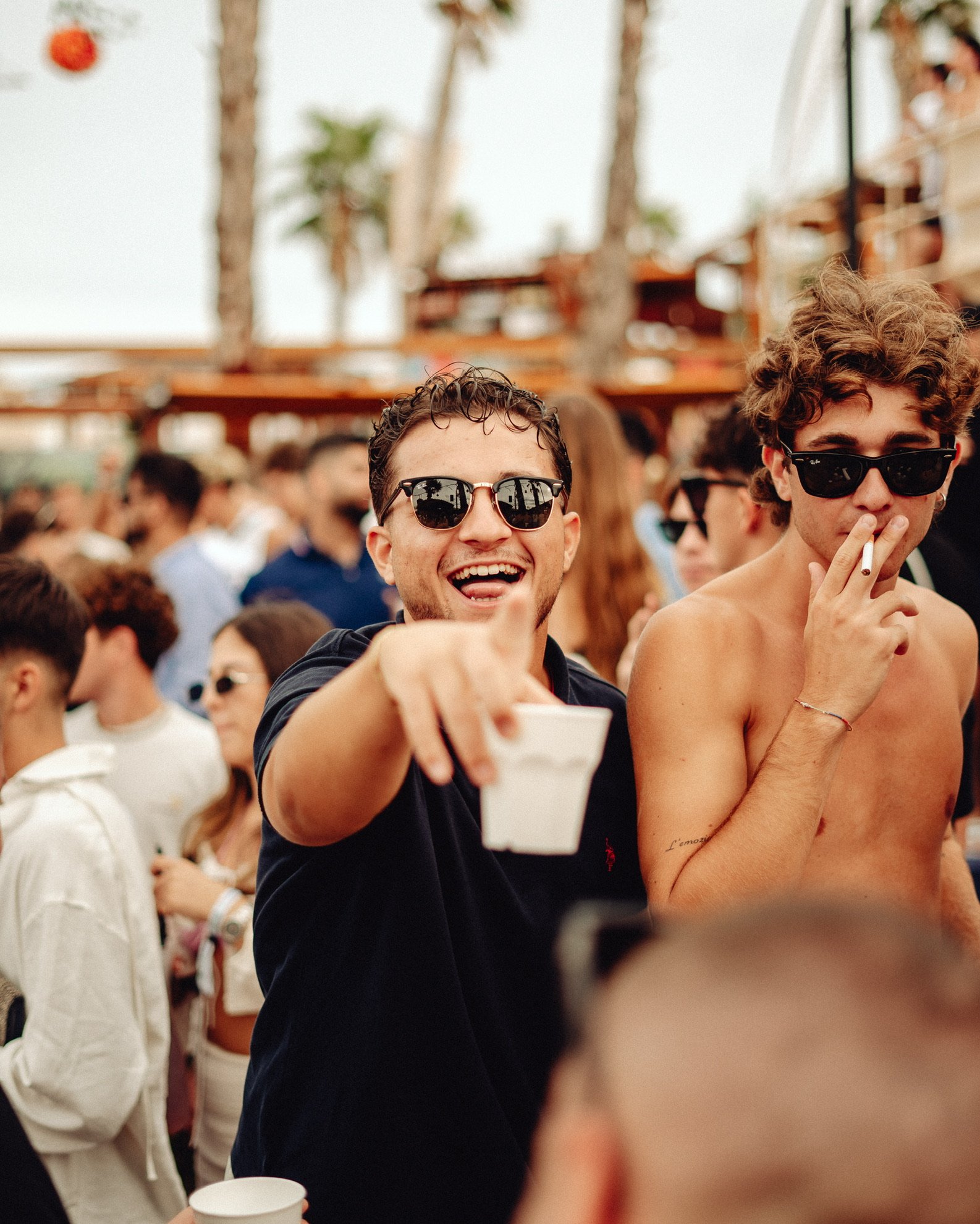 Menschen feiern auf einer Party im Freien, einige tragen Sonnenbrillen, lachen und unterhalten sich.