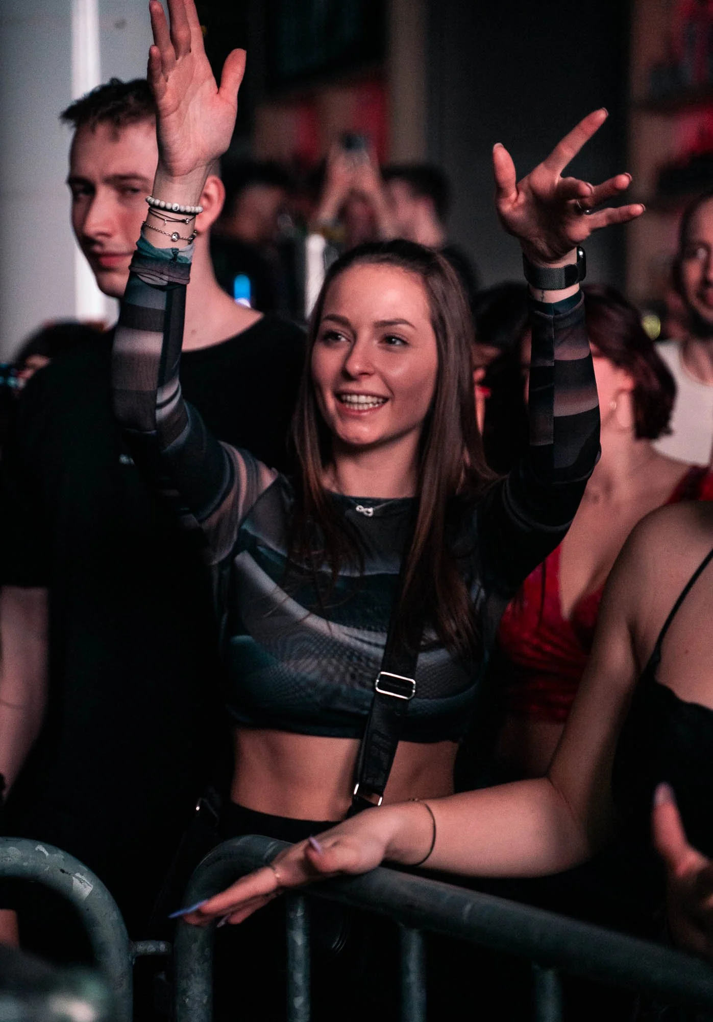 Junge Frau auf einem Konzert tanzt und lächelt, während sie die Hände hebt, um die Stimmung zu genießen.