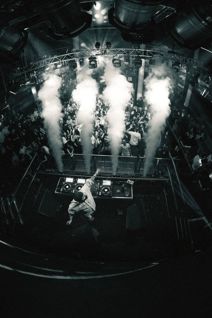 Tanzende Menschen im Dunkelclub mit DJs und Rauch bei einer Party