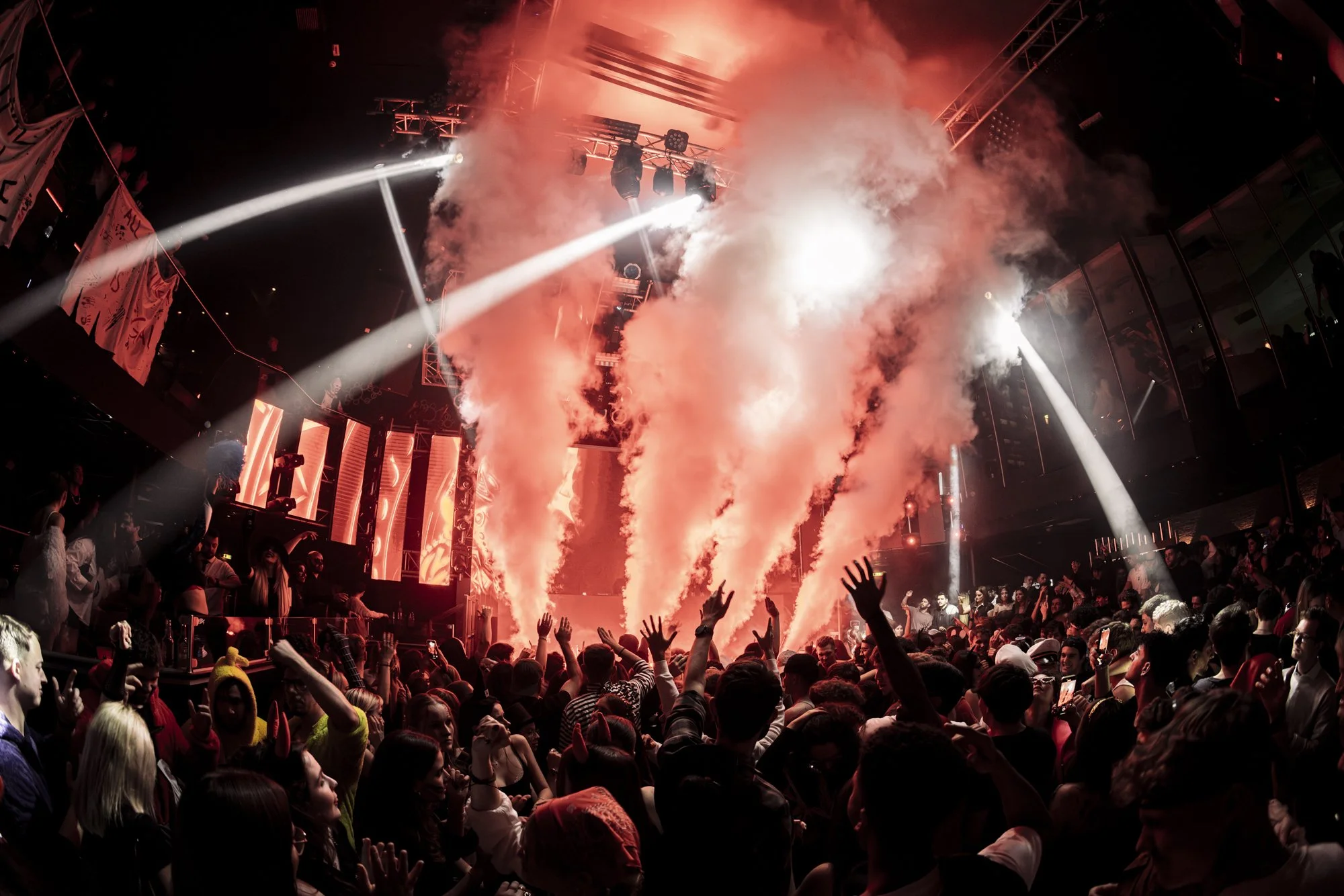 Menschen tanzen und feiern bei einem Konzert oder einer Party mit roten Lichtern, Nebel und Scheinwerfern.