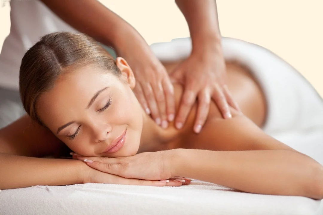 A woman receiving a back massage while lying face down with a relaxed expression.