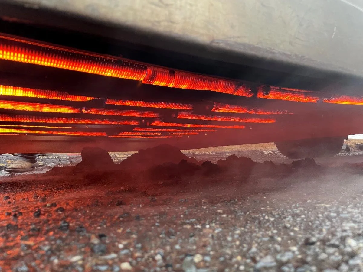 Close-up of car underneath, showing red LED underglow lights reflecting on the ground and dirt.
