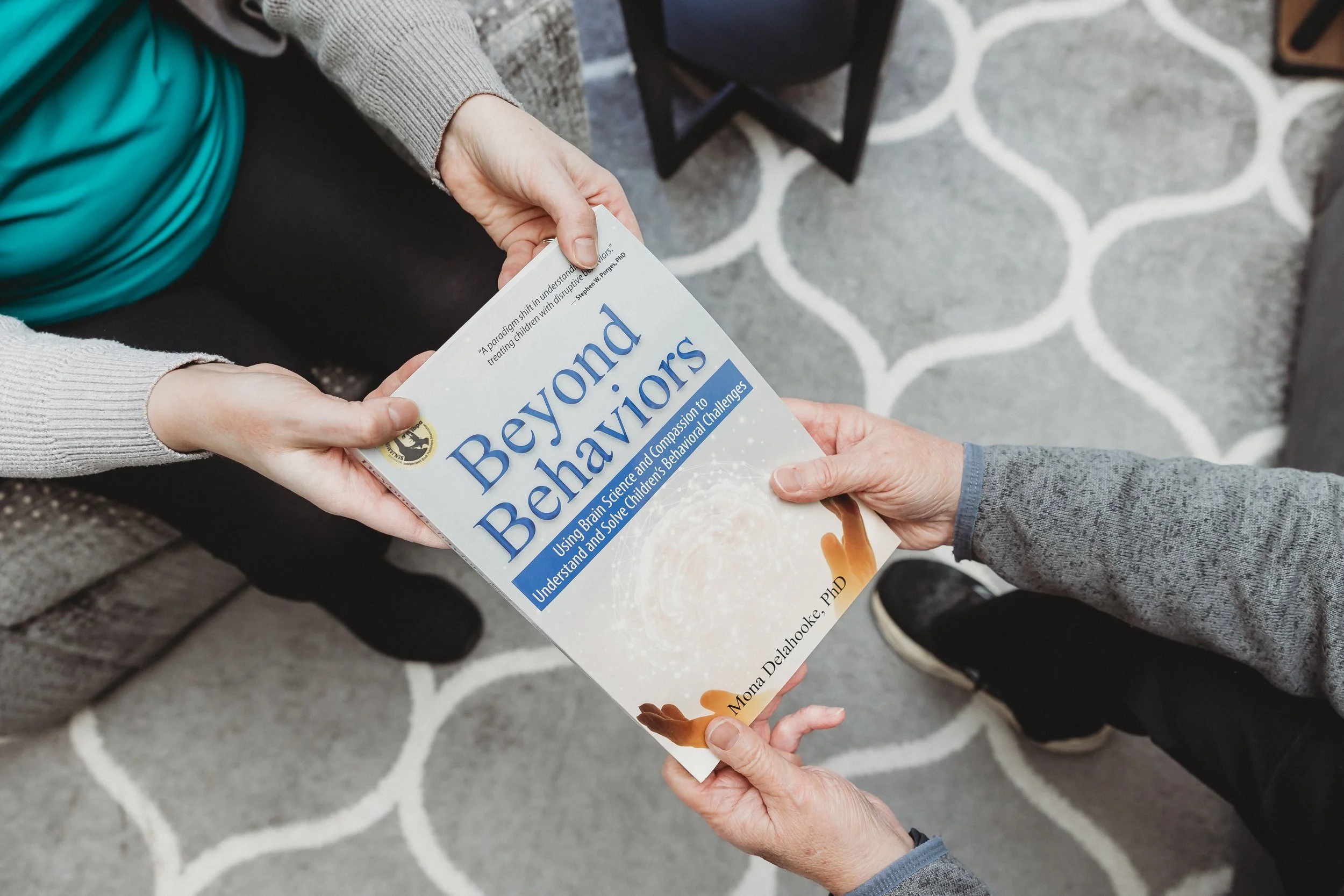therapist handing client a book about parenting called Beyond Behaviors