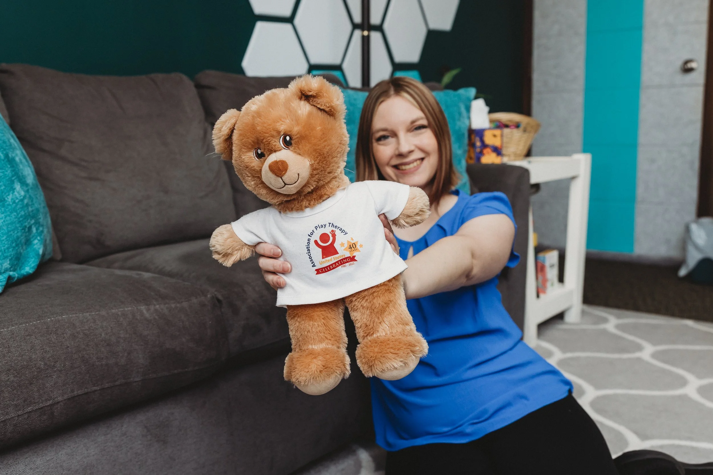Therapist smiling with a stuffed bear representing a new baby