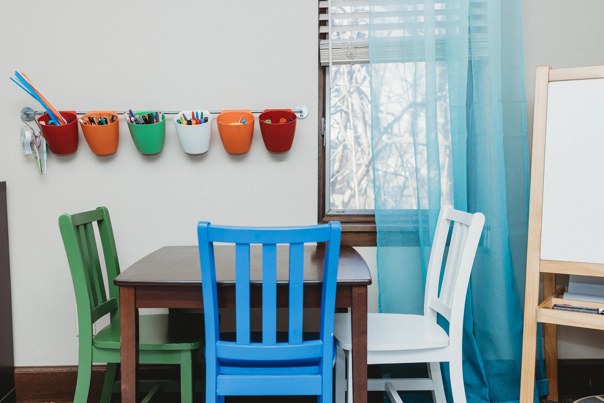 children's art table with a variety of colors and buckets with paint supplies and markers