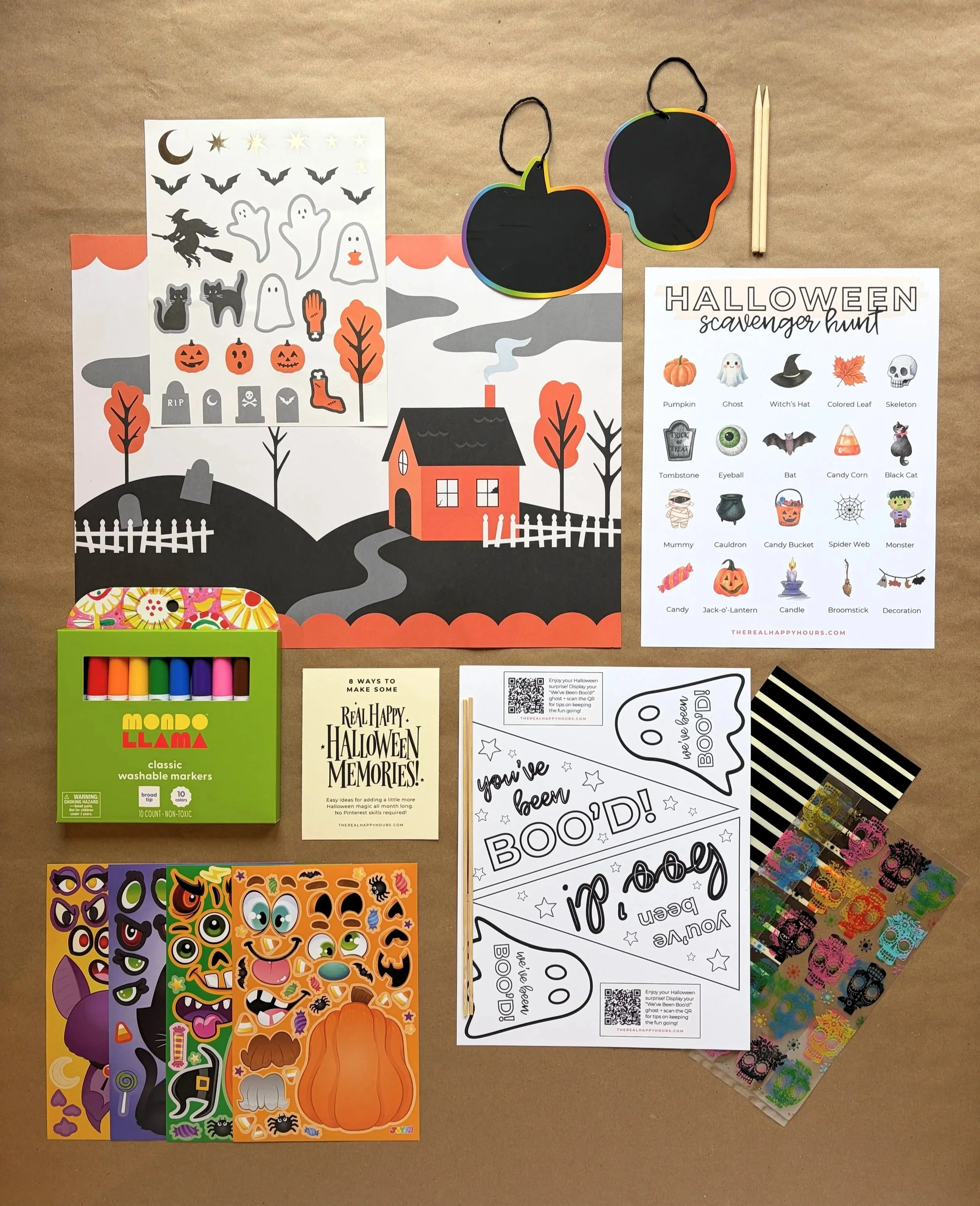 Kids Halloween activity box flat lay with coloring placemat, washable markers, scavenger hunt, sticker activities, scratch art, activity cards and mini You’ve Been Boo’d kits