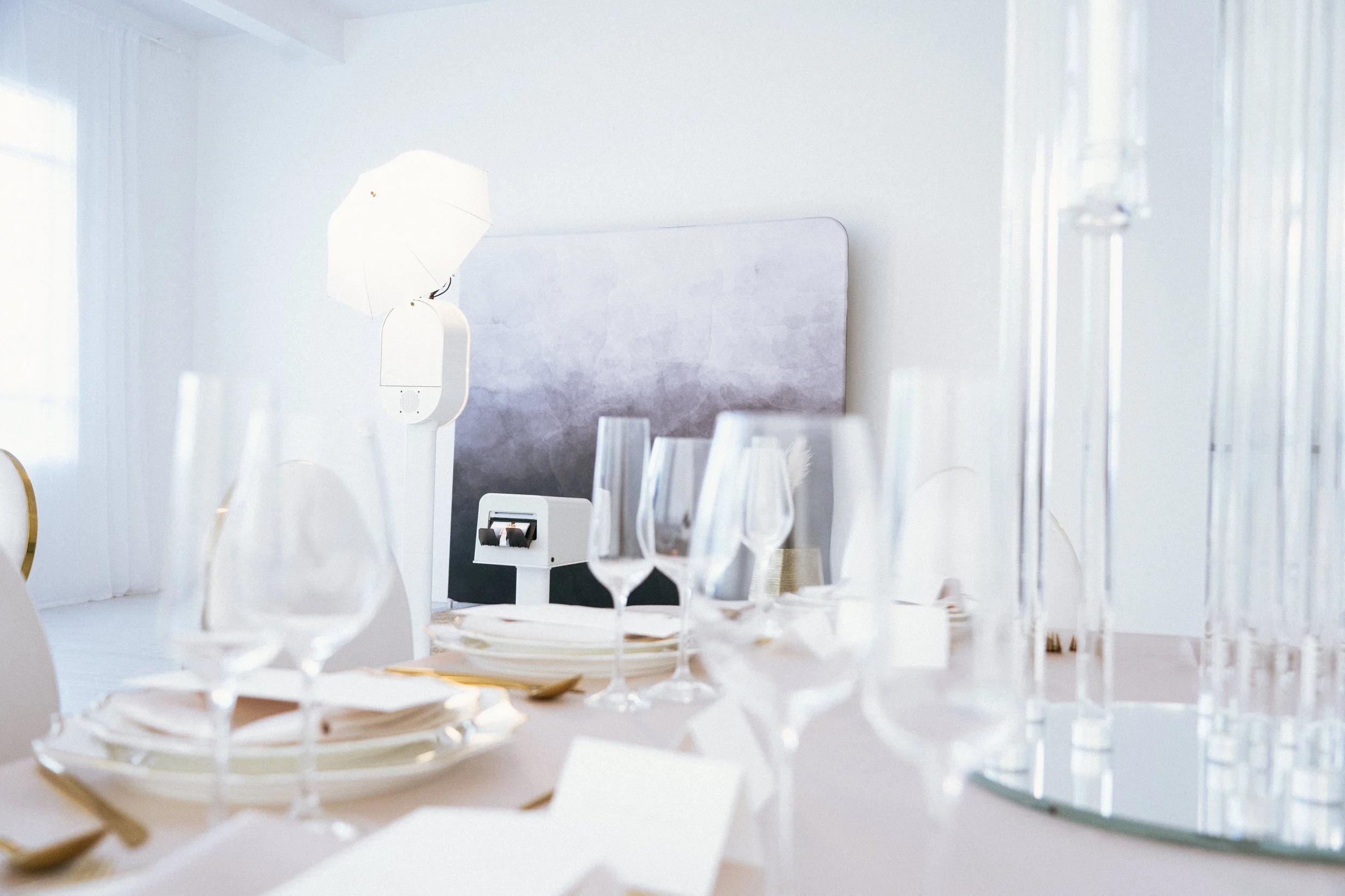 Elegant table setting with champagne flutes, plates, and cutlery, decorated for a formal event with white and gold accents, and a modern ambient lighting setup.