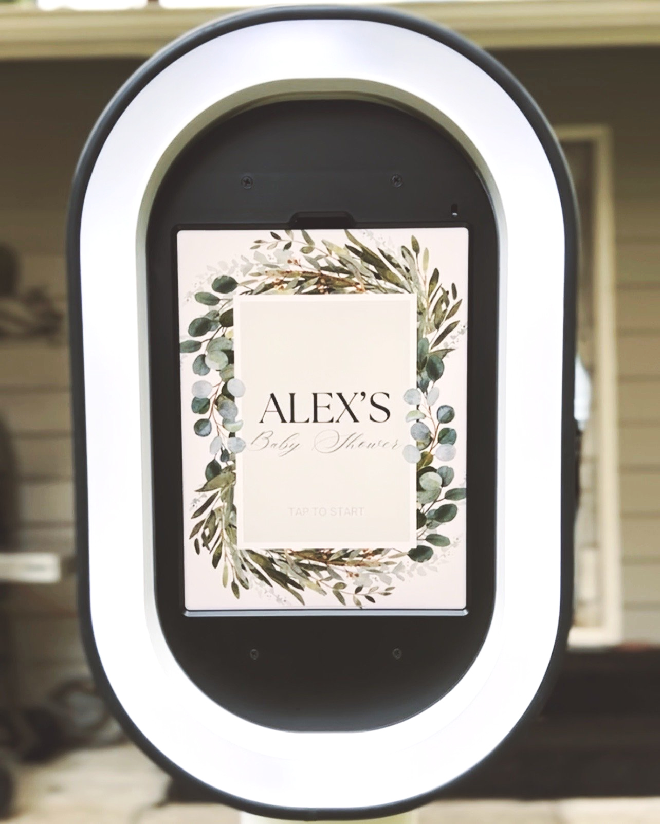Device screen showing a baby shower invitation for Alex, decorated with green leafy and botanical artwork.