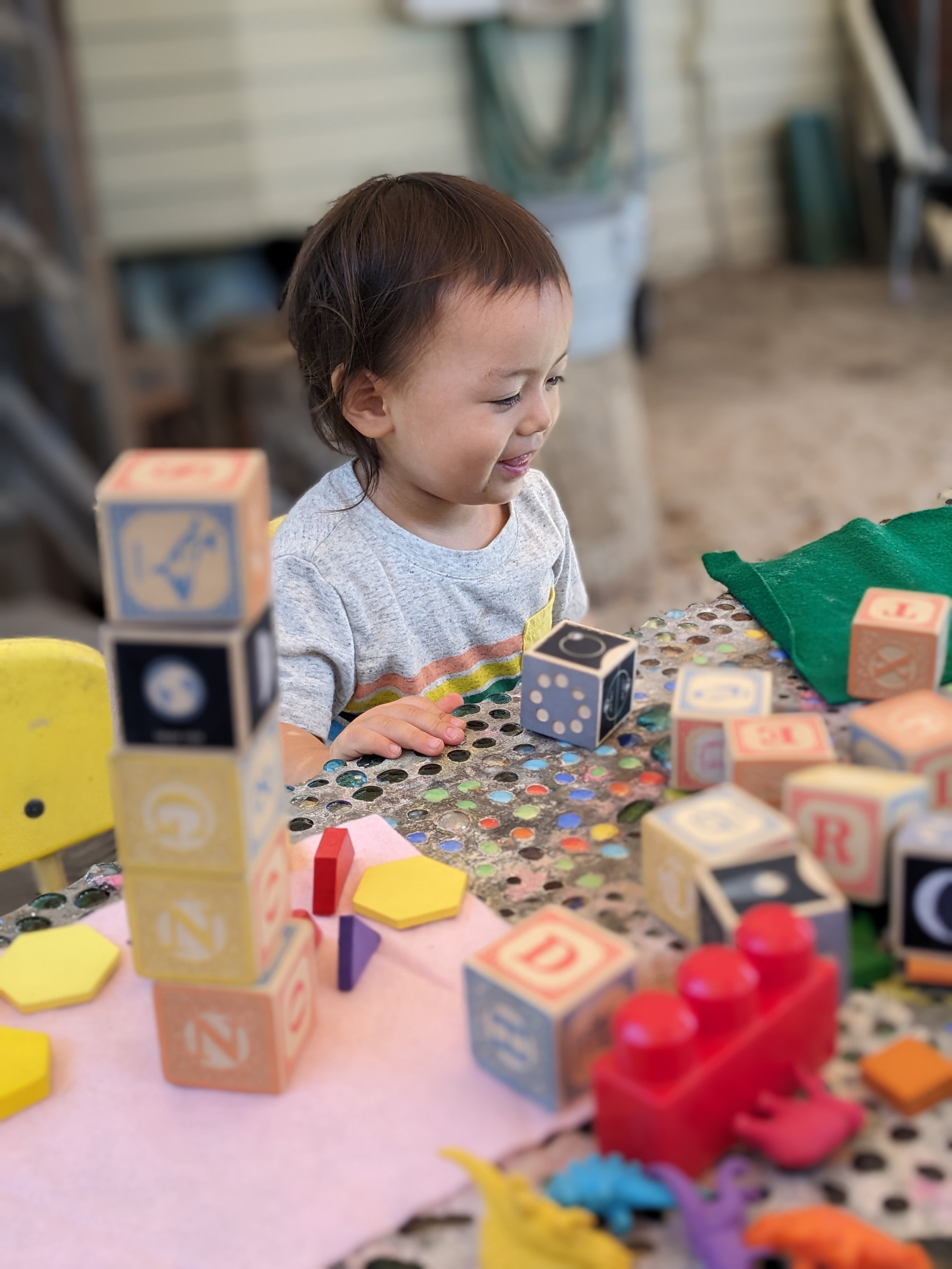 Little child smiling, playing with blocks.
