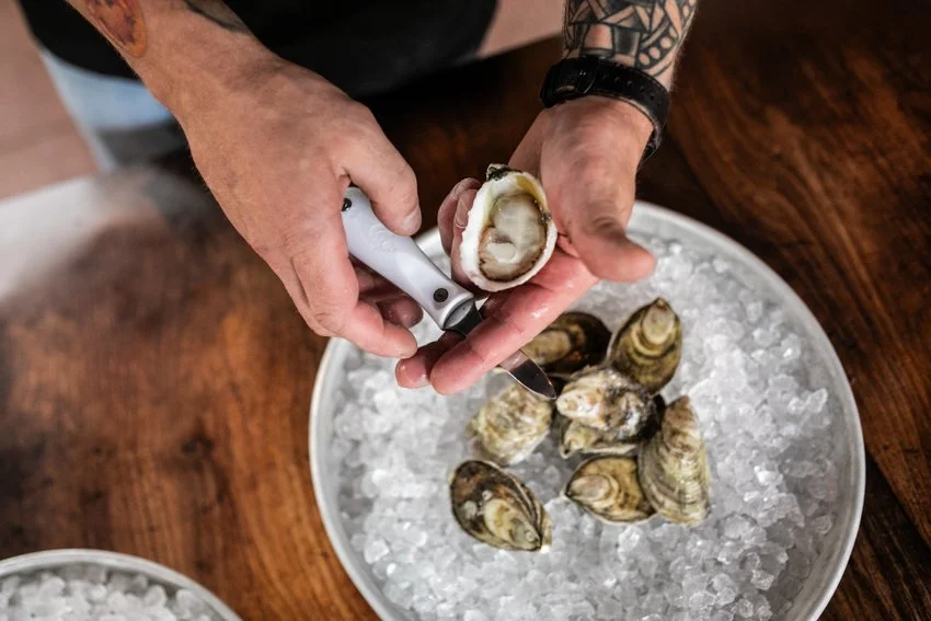 hand holding an oyster and an oyster knife