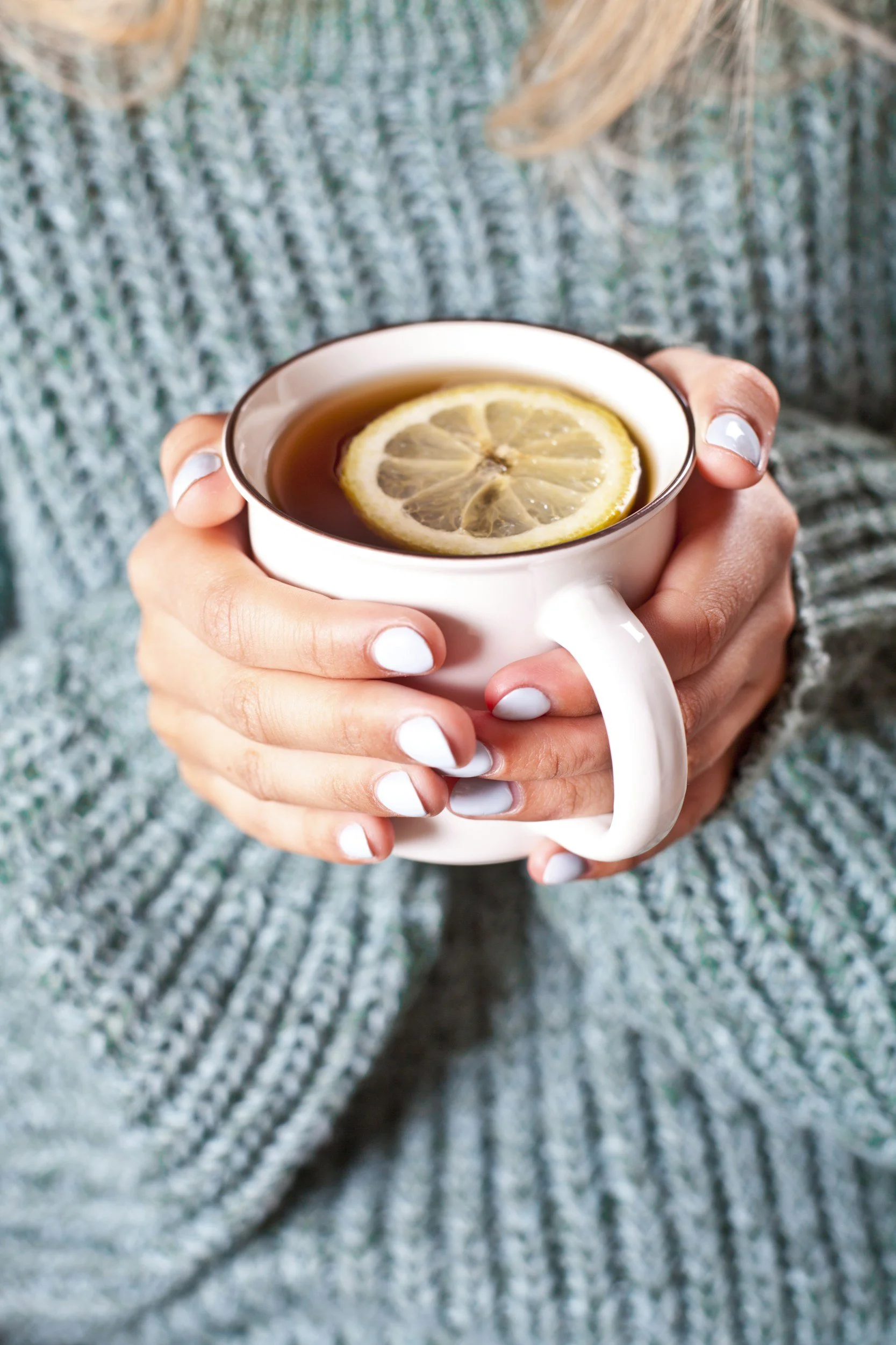 Person holding a white mug with a lemon slice inside, a calm scene for someone seeking trauma therapy.