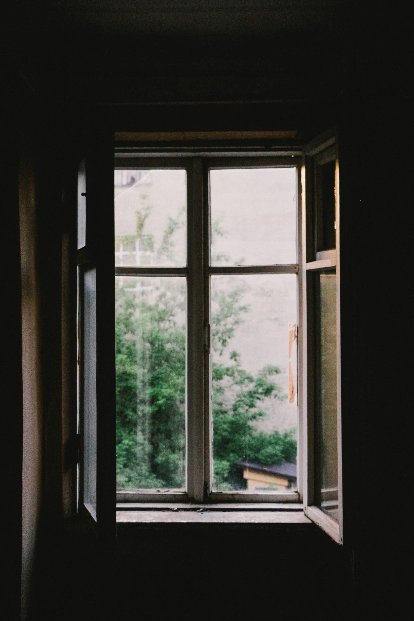 Open window with view of trees and sky outside.
