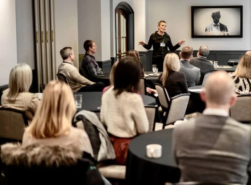 A woman giving a presentation to an audience in a conference room.
