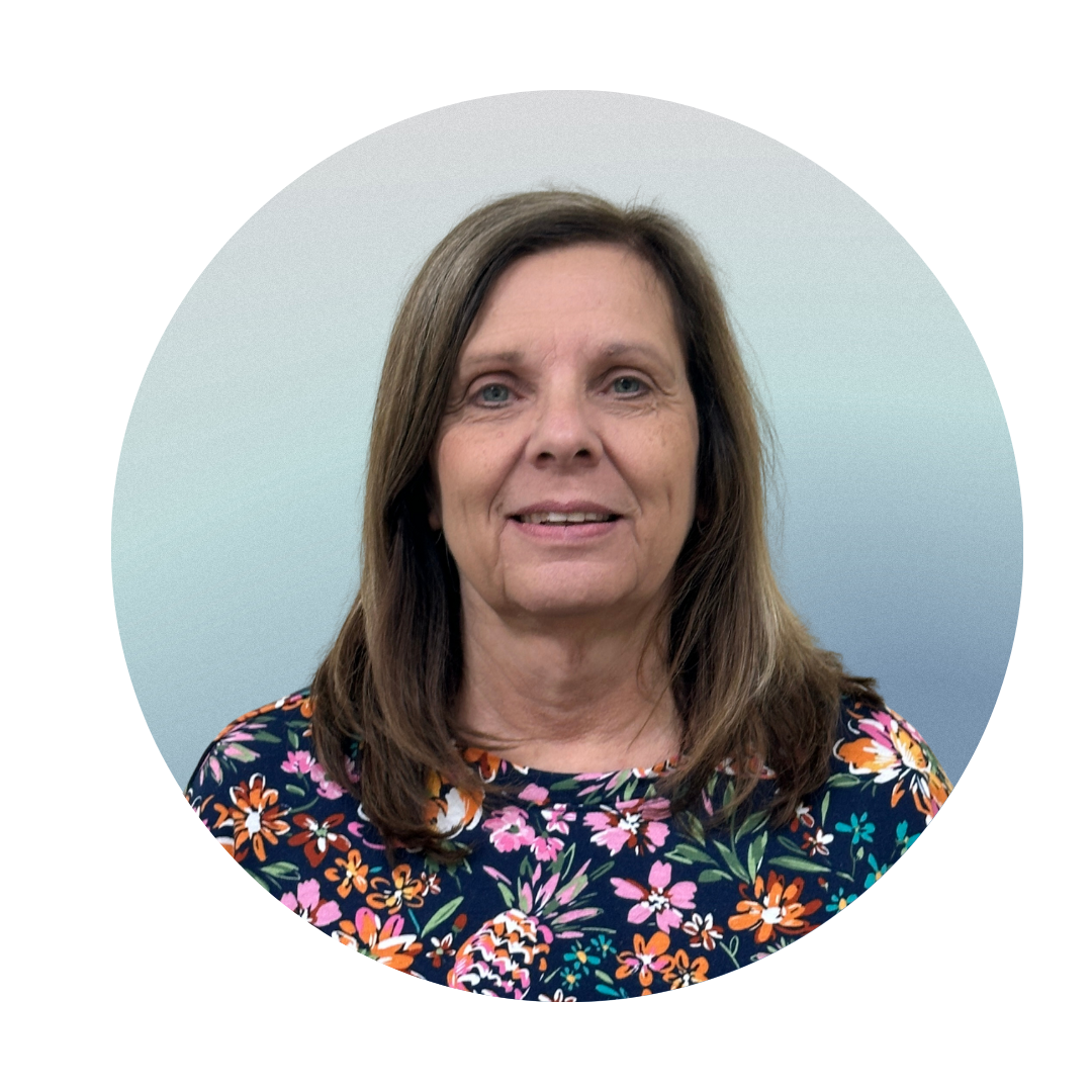 A woman with shoulder-length brown hair wearing a colorful floral top, standing against a light gradient background.