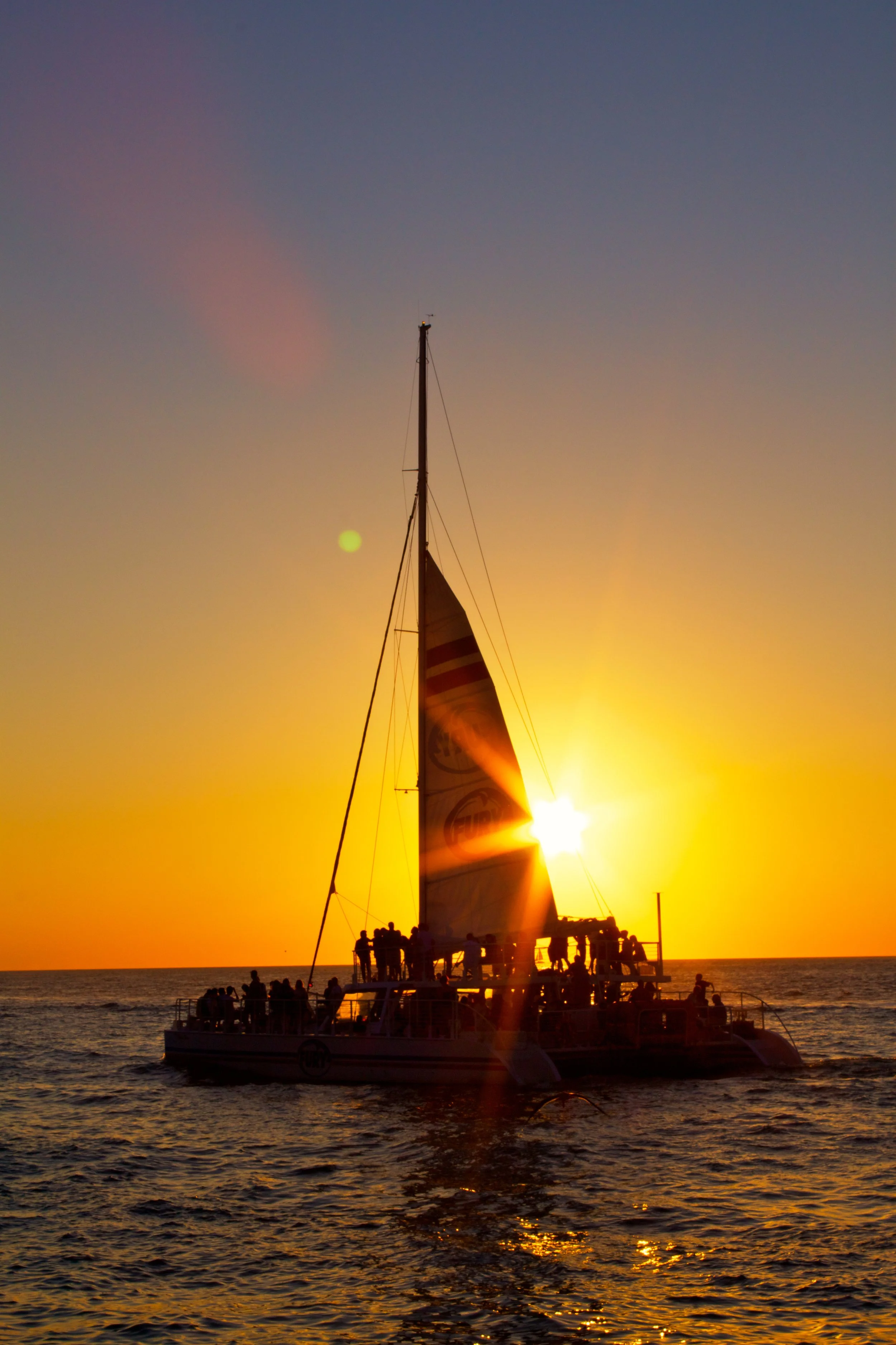 Photo of the sunset over a sail boat.