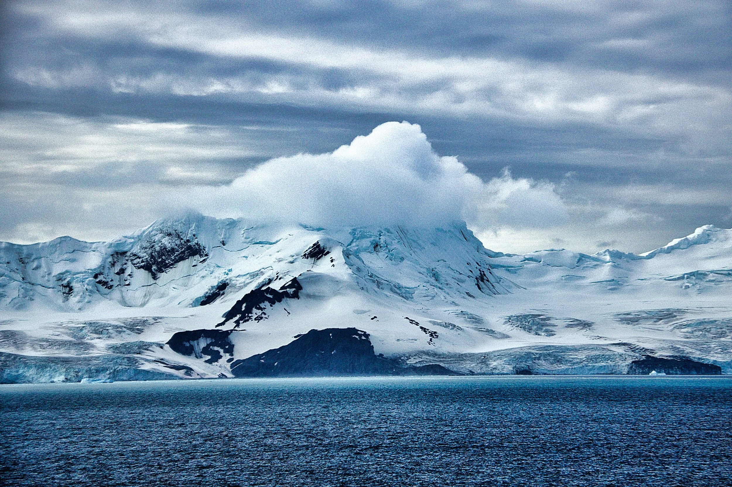 Snow covered mountain in Antartica surrounded by the Antarctic Ocean. 