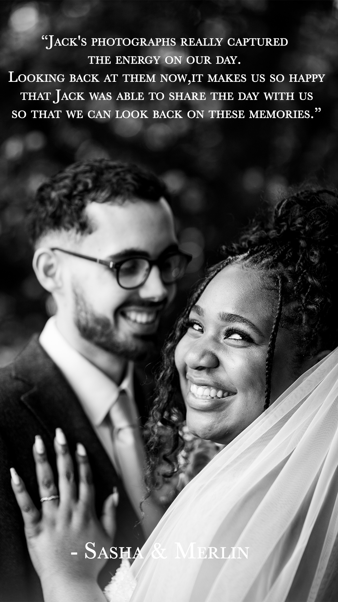 Black and white photo of a happy couple, Sasha and Merlin, smiling at each other. The man wears glasses and a suit, while the woman has curly hair and is wearing a veil. Their faces are close, and they seem joyful.