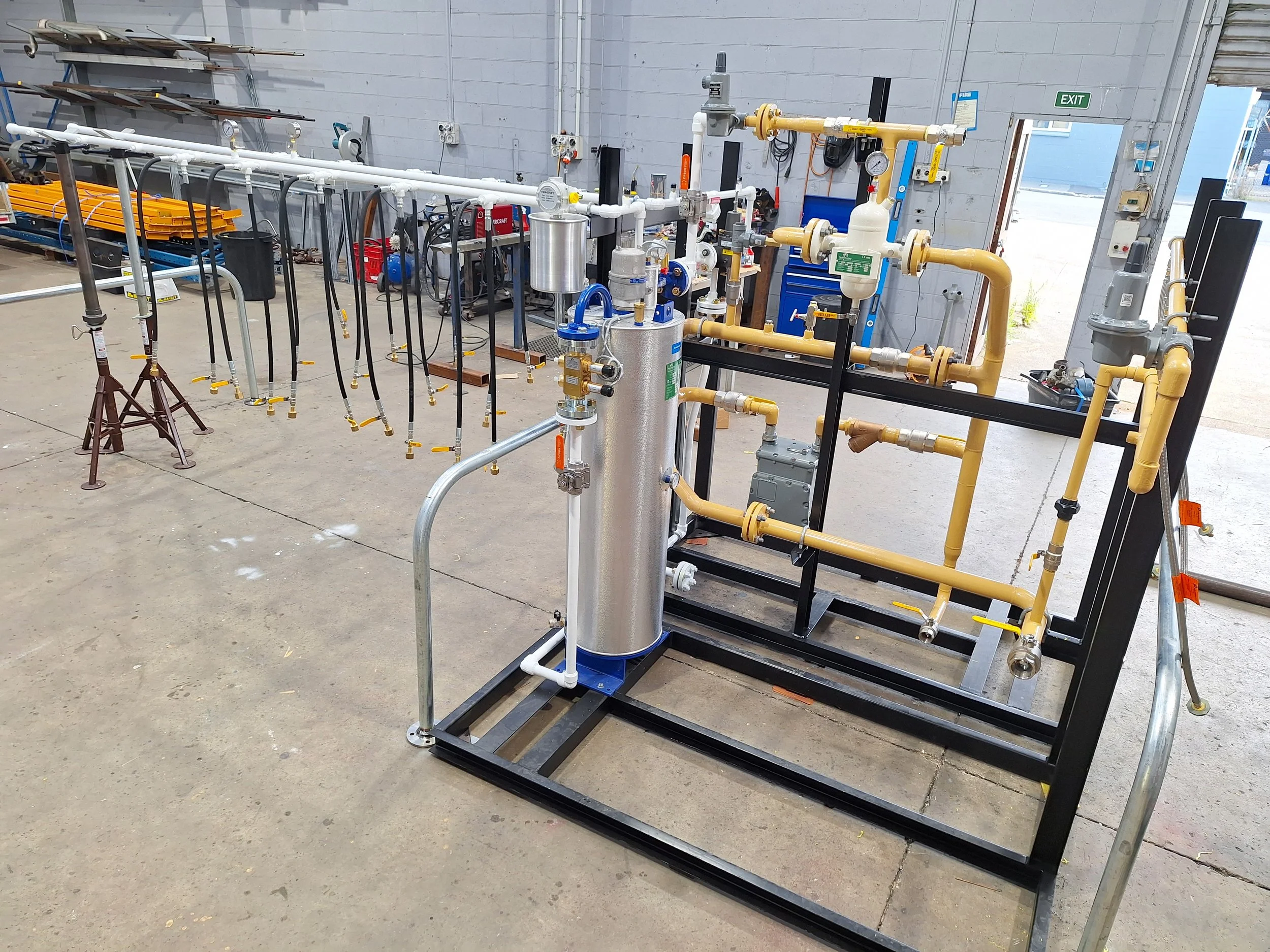 Industrial piping and equipment setup in a warehouse with blue storage cabinet, yellow pipes, and gauges.