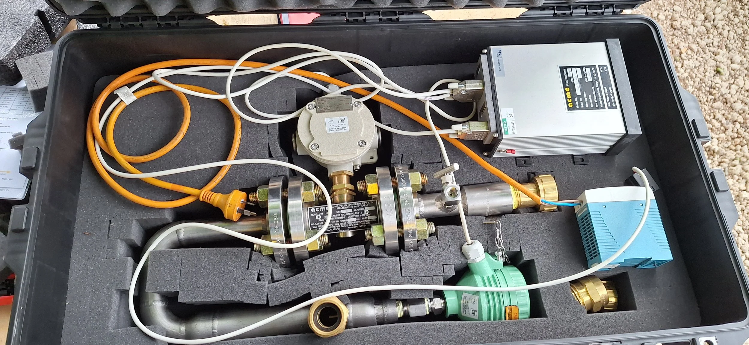 A portable setup with various electronic and hydraulic components, including pipes, wires, a power supply, and control units inside a foam-lined case.