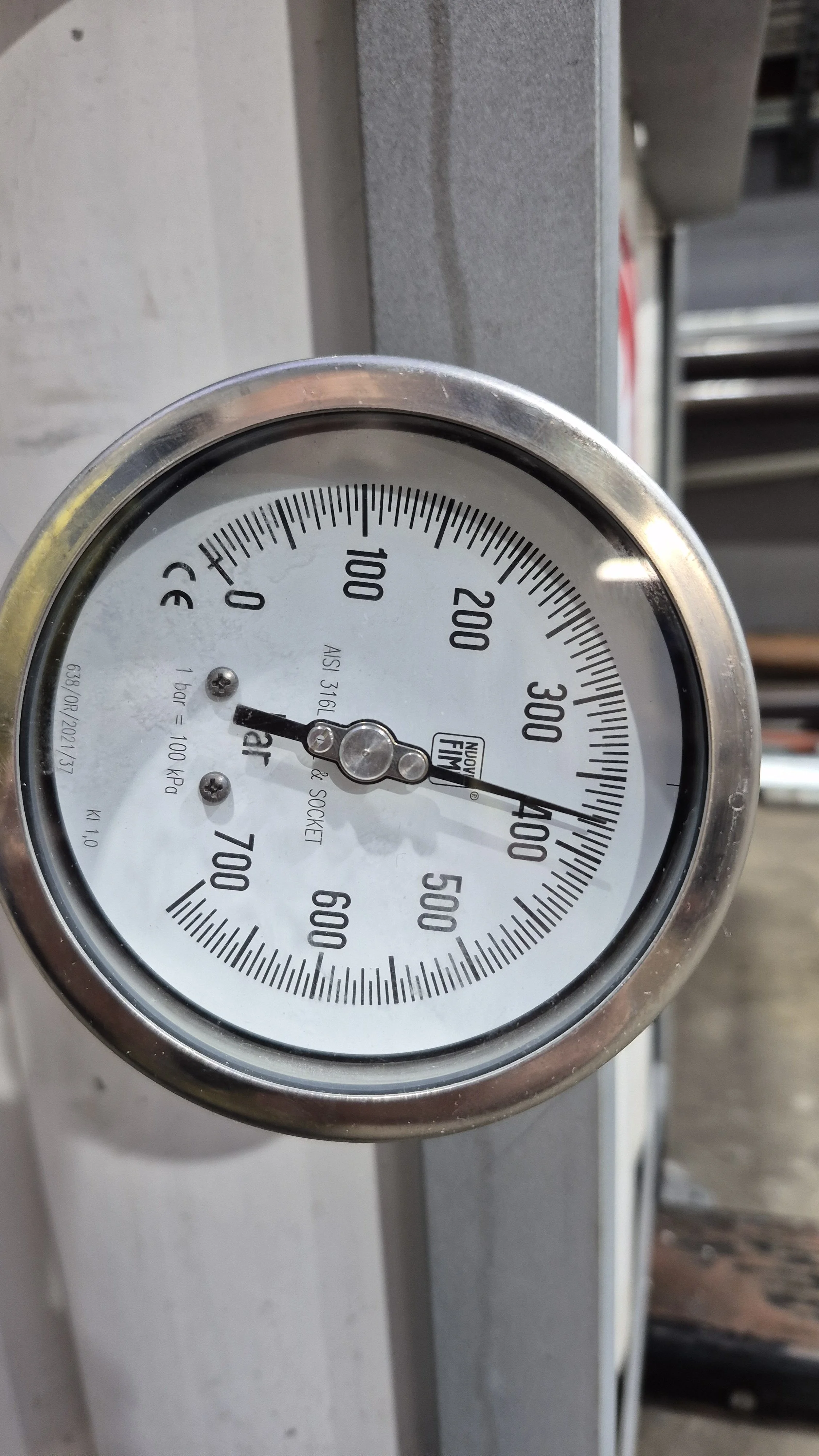 Close-up of a round pressure gauge measuring in PSI, mounted on a metal surface.