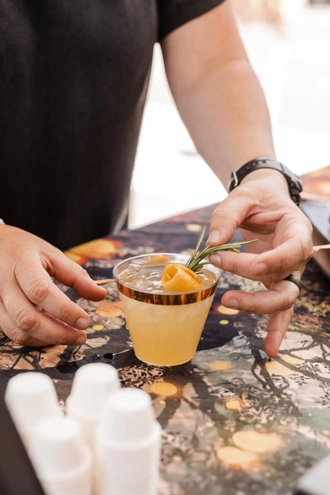 mixologist garnishing a yellow mocktail with a sprig of rosemary