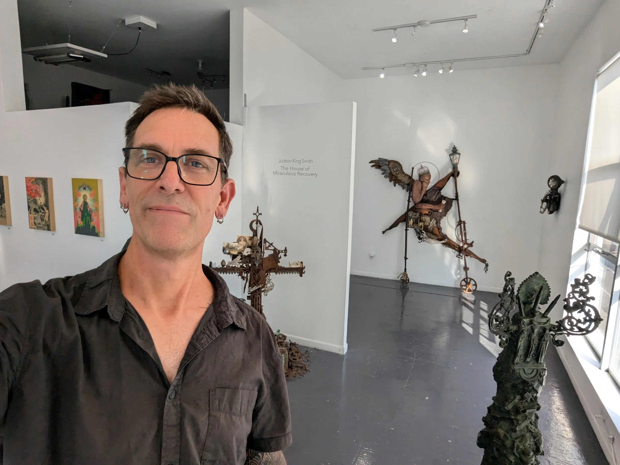 Judson King Smith standing before multiple sculptures in a gallery