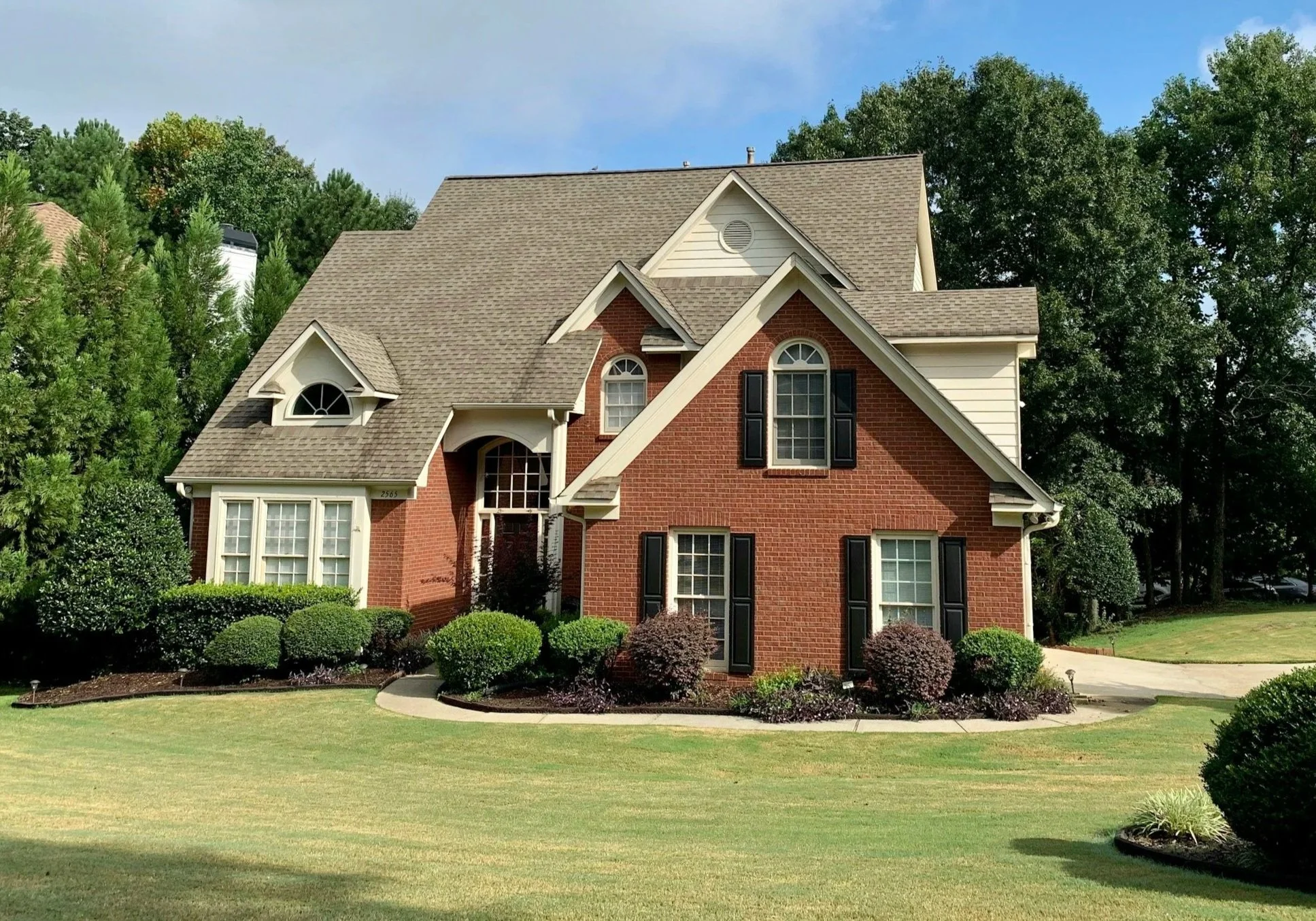 Staged two-story brick home exterior with black shutters and manicured lawn in Seattle.