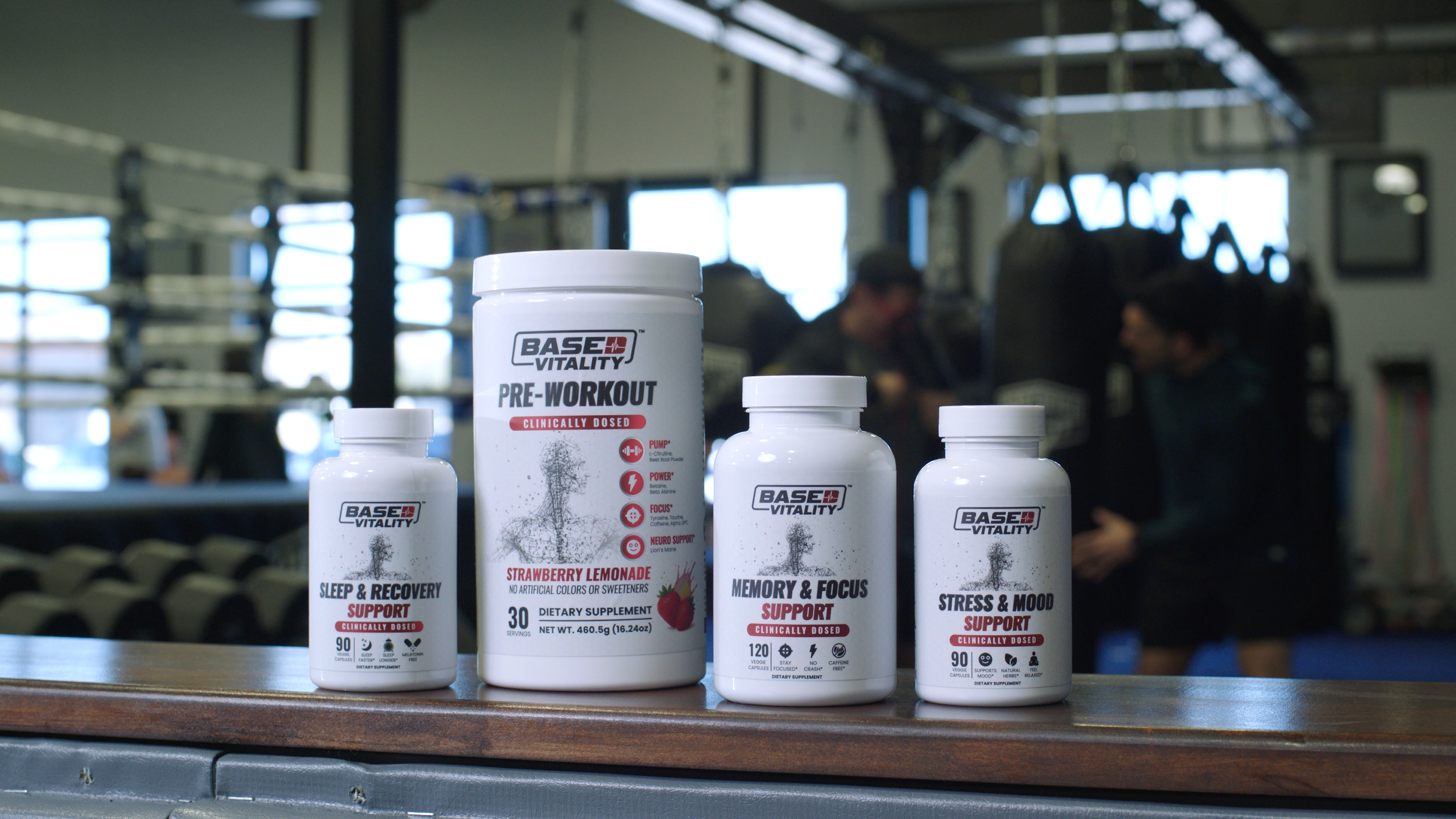 Four bottles of dietary supplements on a gym counter with a boxing gym in the background.