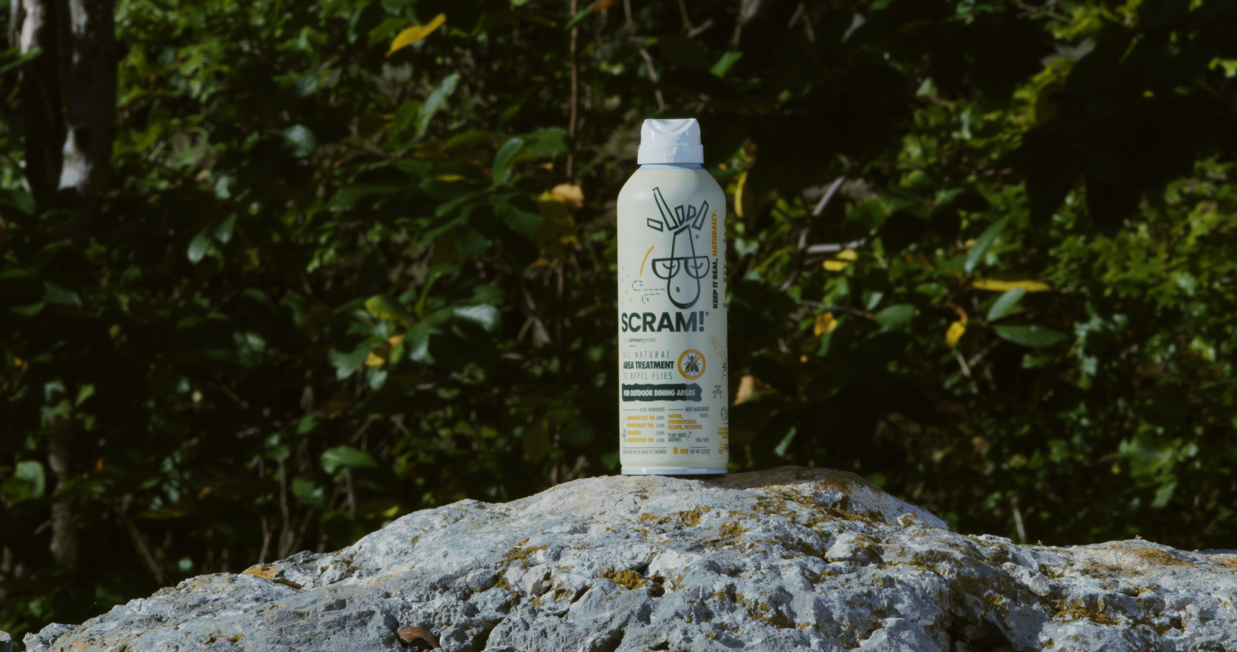 Can of SCRAM! insect repellent spray placed on a rock outdoors, with green foliage in the backgroundproduction company Fort Worth. video production.