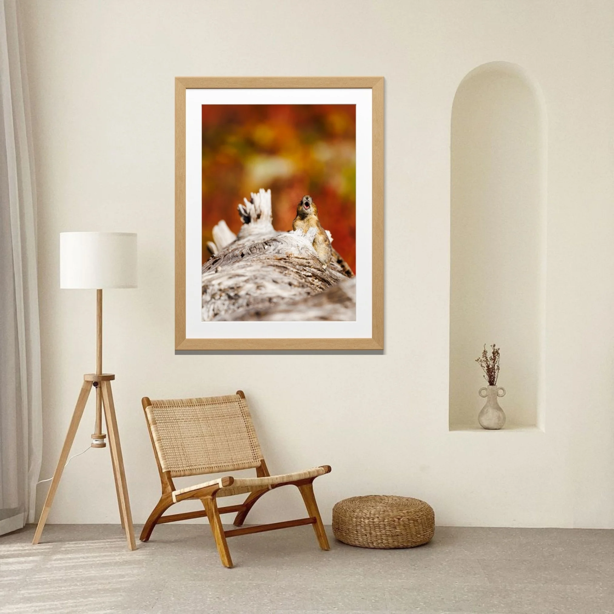 A framed limited edition fine art print of a pika sits above a chair in the corner of a living room.