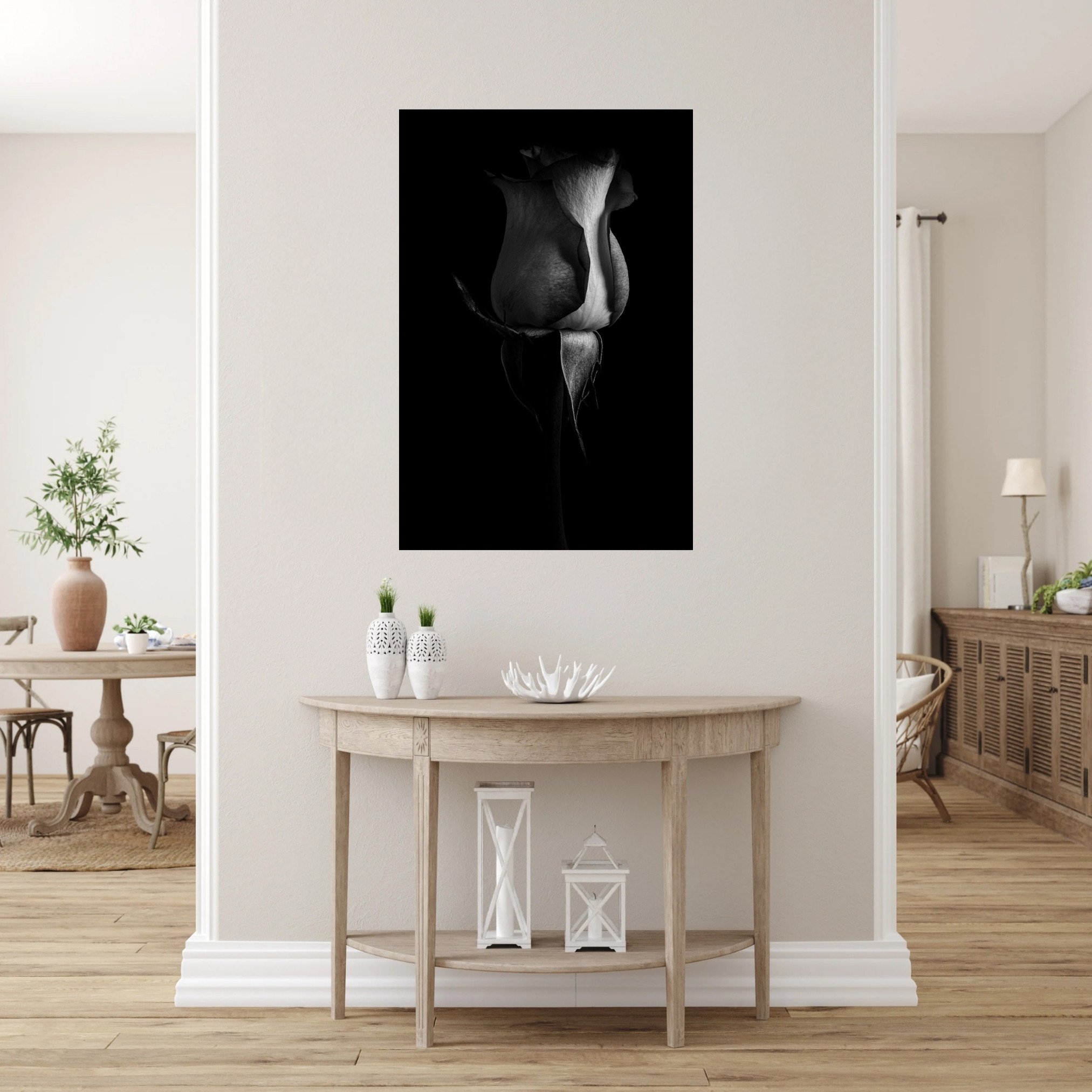 A black and white photo of a rose sits between two room openings on a white wall above a semi moon table.