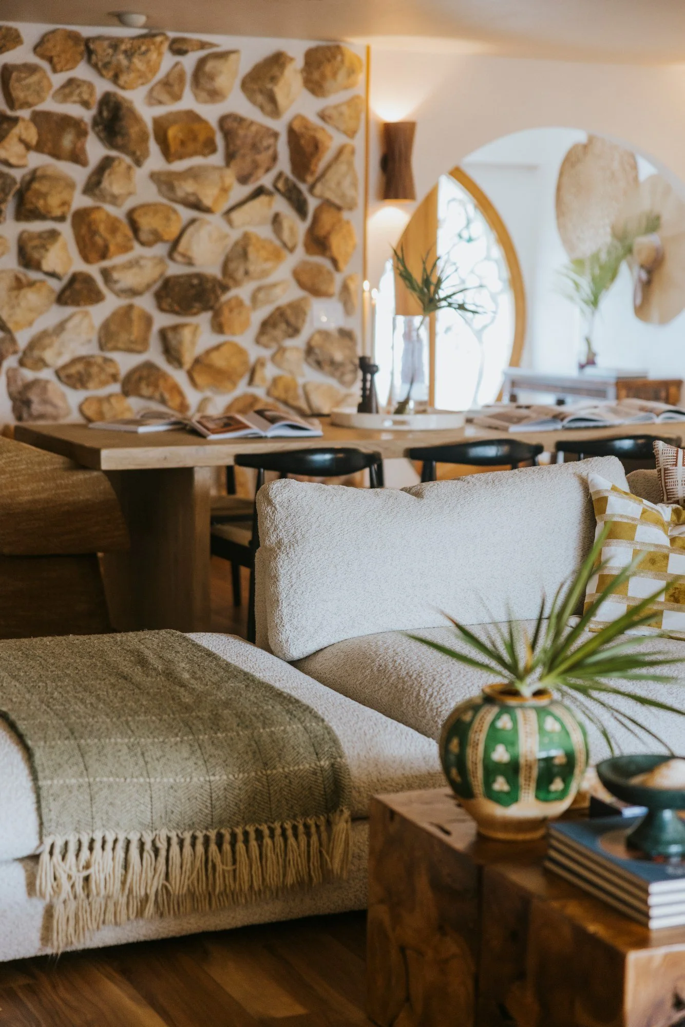 Beau Beau lounge with textured seating, stone wall and a dining table beyond