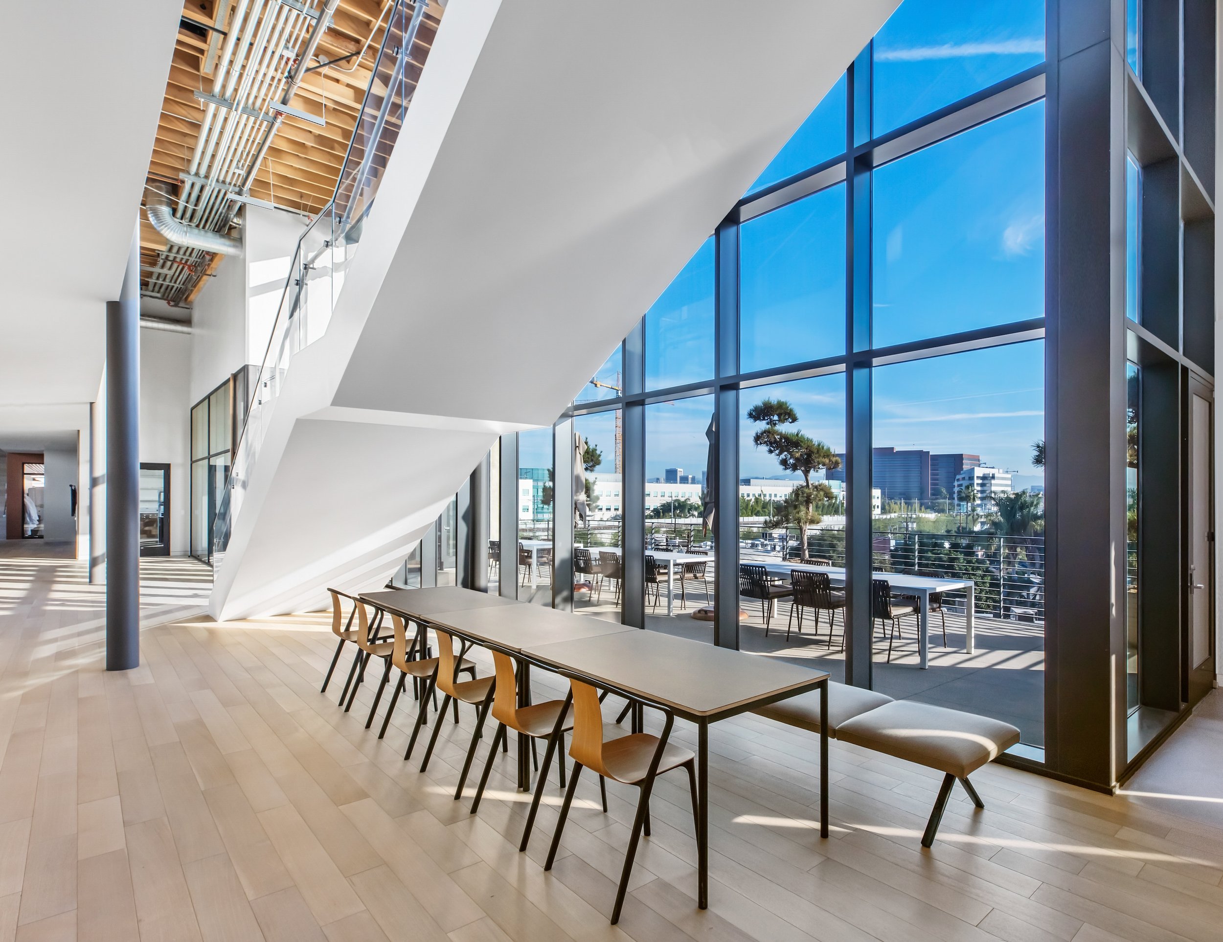 Modern office with large windows, long table with chairs, and staircase