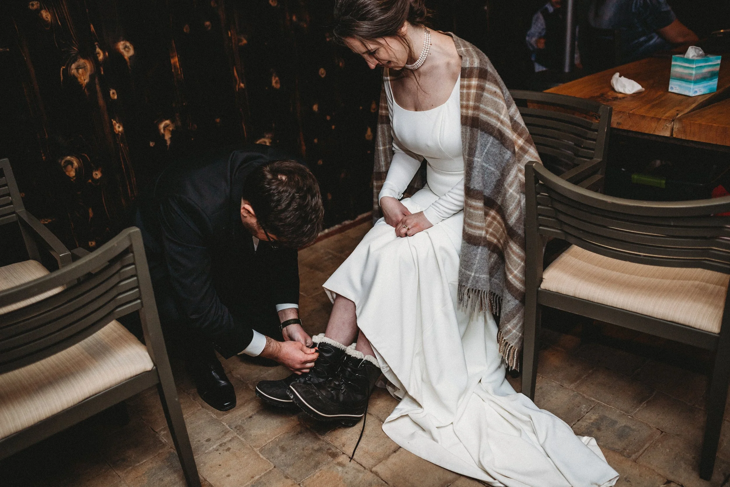 Groom putting boots on bride winter wedding kansas