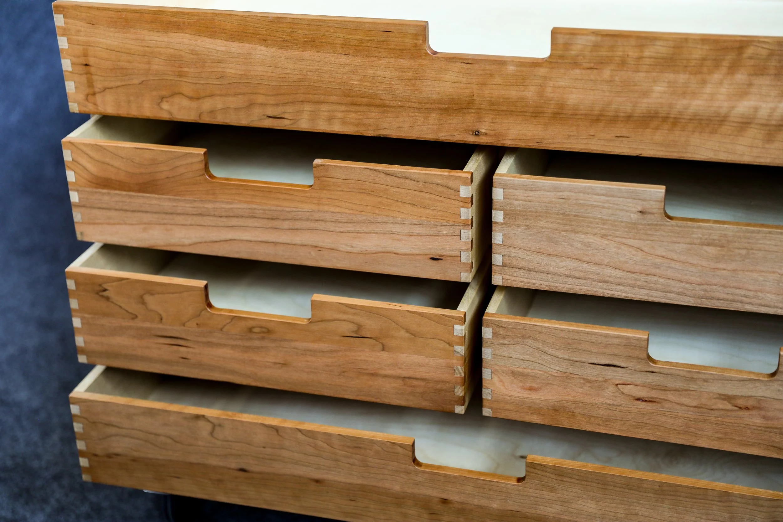 Wooden drawers with dovetail joints, partially open, stacked vertically.