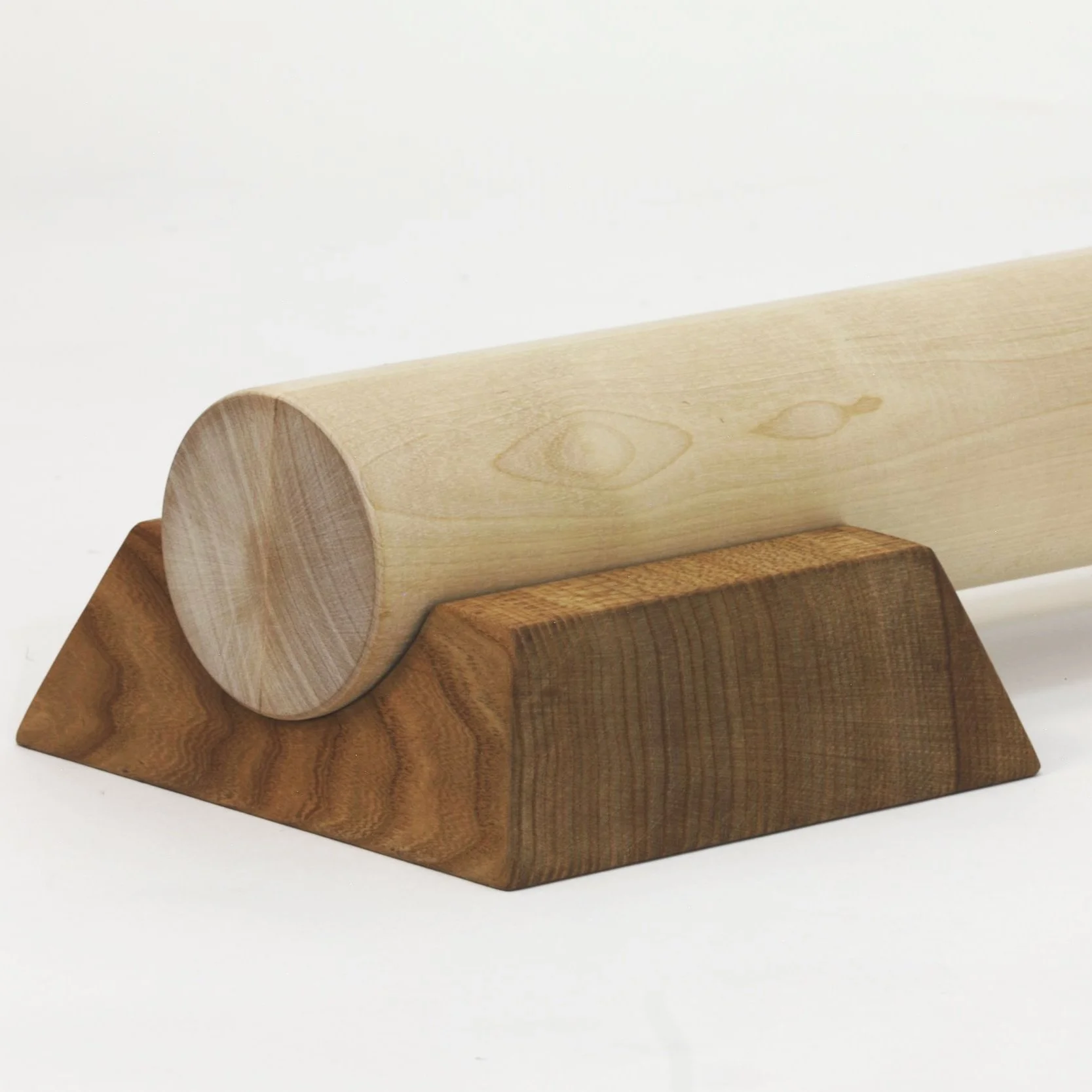 A wooden rolling pin resting on a wooden stand on a white background.