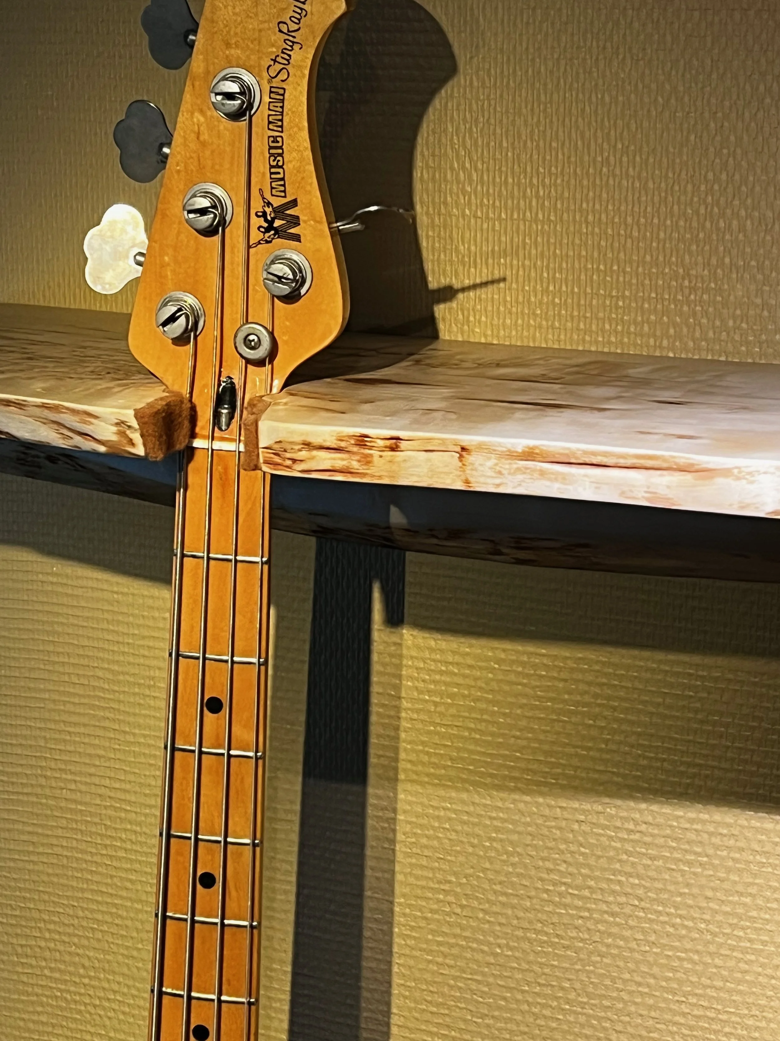 Close-up of the headstock of a Fender Classic Series 60s Jazz Bass guitar with four tuning pegs, strings, and a logo that reads "Music Man StingRay".