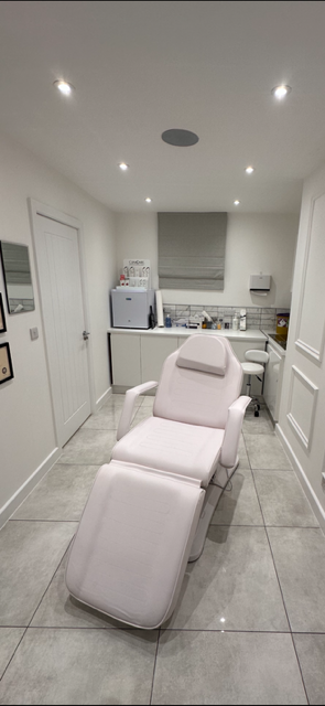 Medical examination room with a white reclining chair, cabinets, and medical supplies.