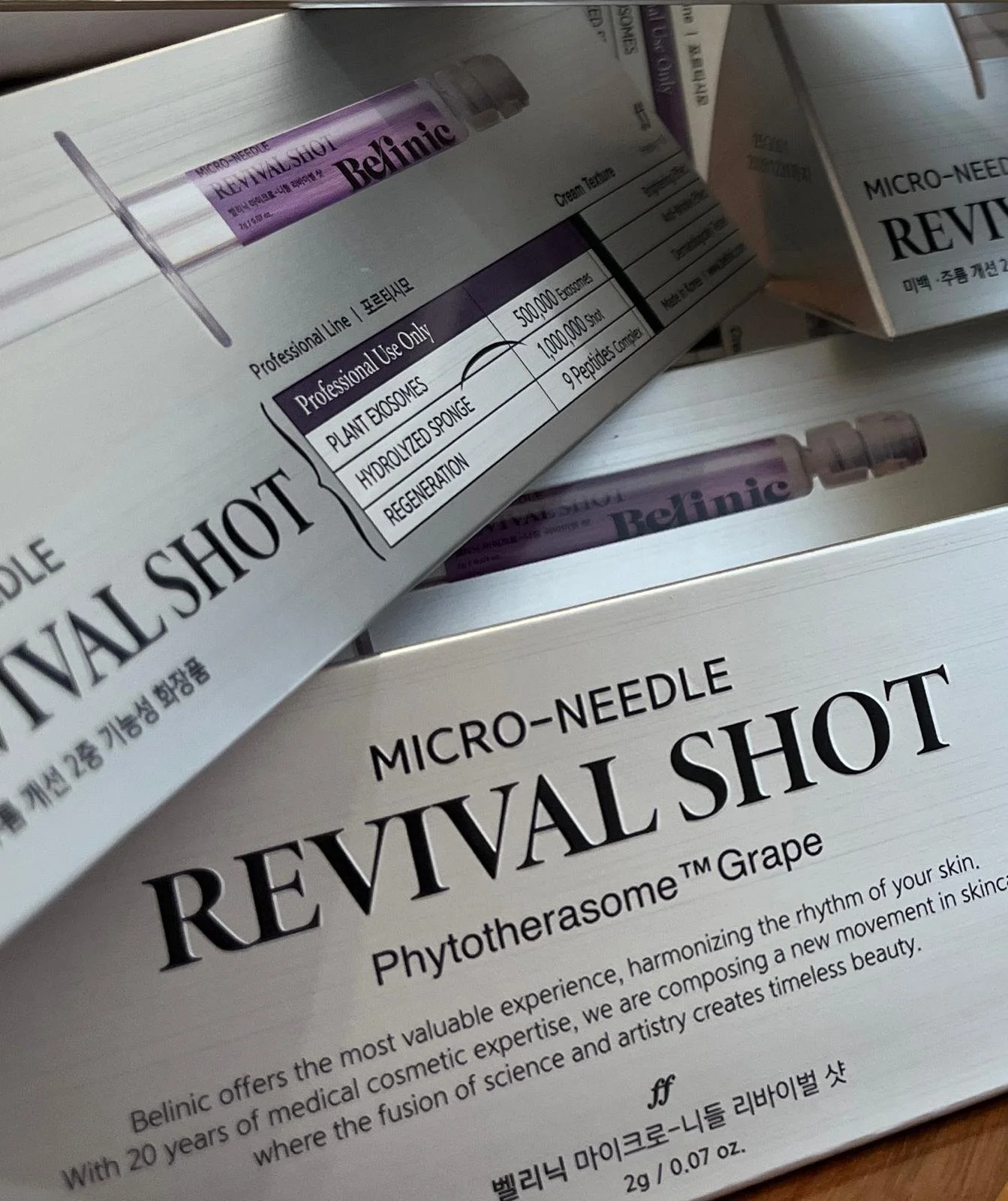 Multiple boxes of Micro-Needle Revival Shot skincare product with purple and white packaging. For a Needle-Free Microneedling.