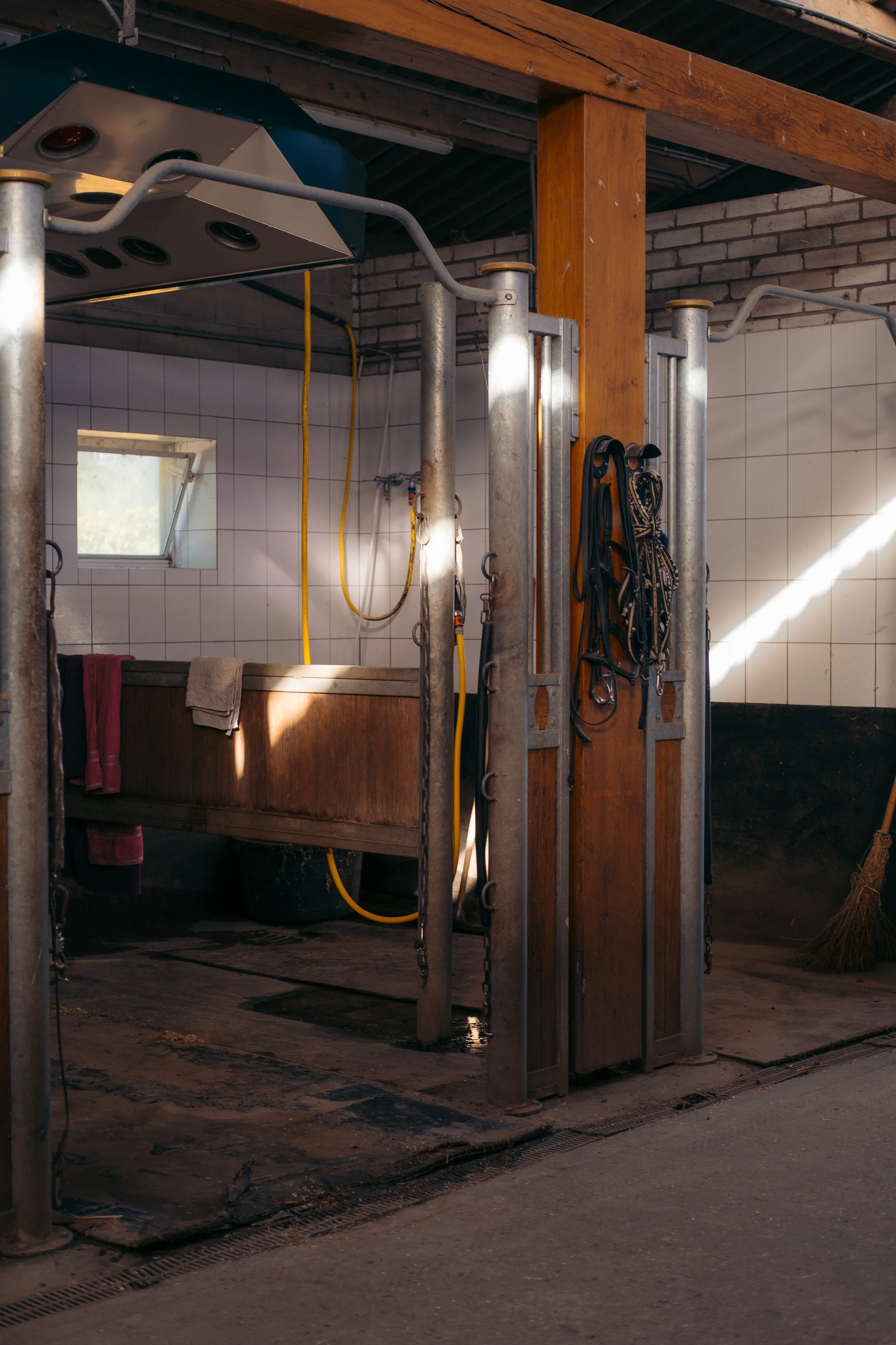 Interieur van een paardenstal met stro, houten balken en zacht licht